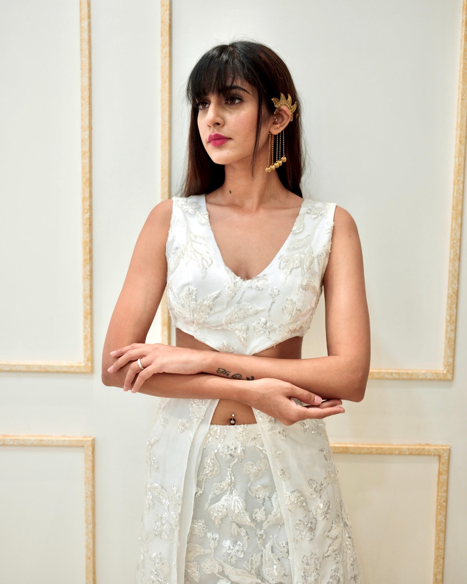 Woman wearing a white embroidered outfit against a light background