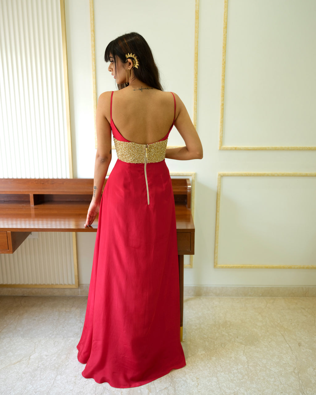 Woman wearing a red dress with a gold top in an indoor setting