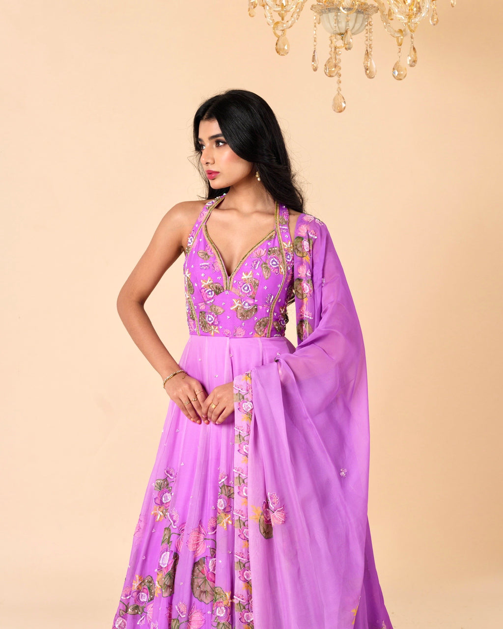 Woman wearing a purple embroidered dress against a beige background