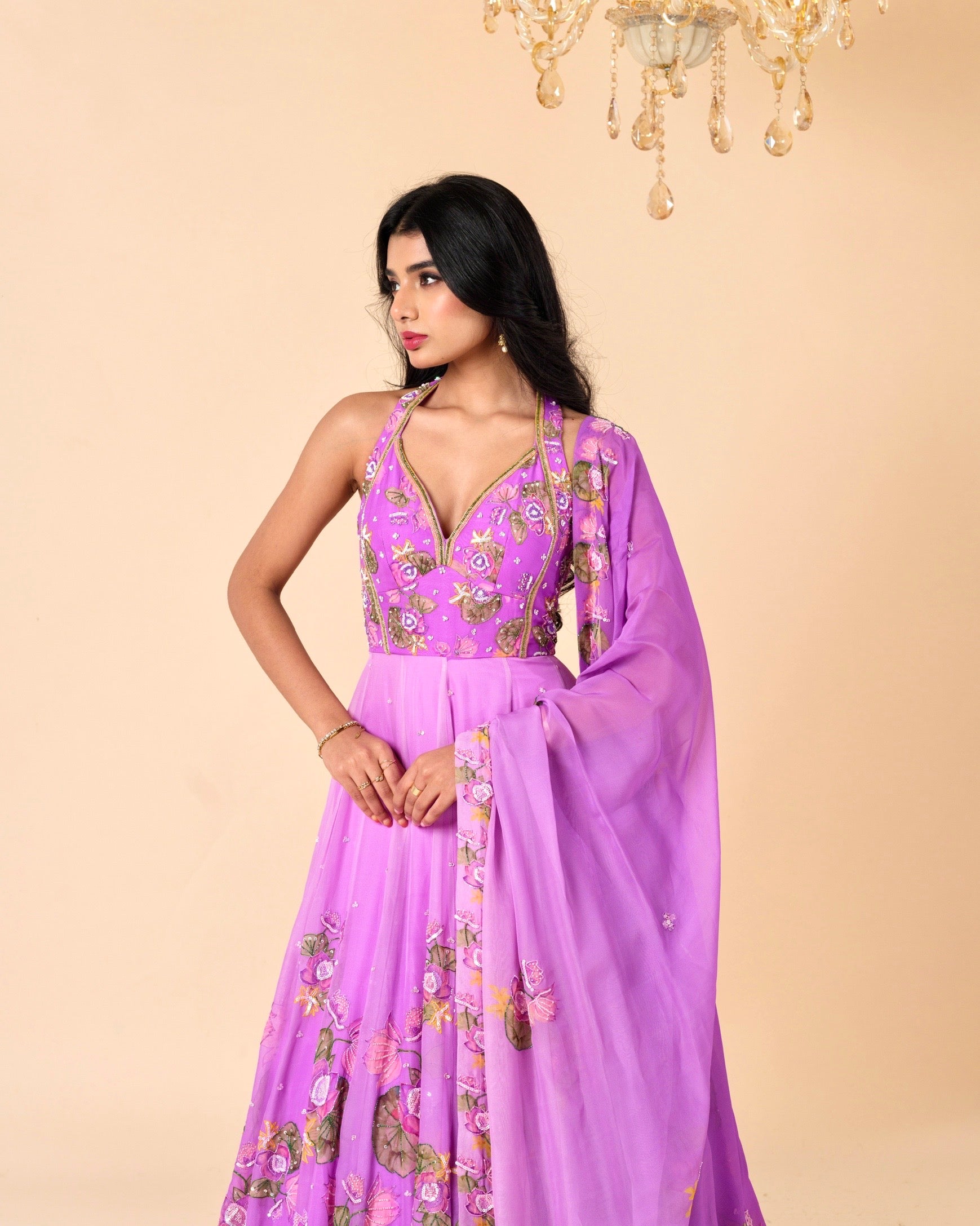 Woman wearing a purple embroidered dress against a beige background