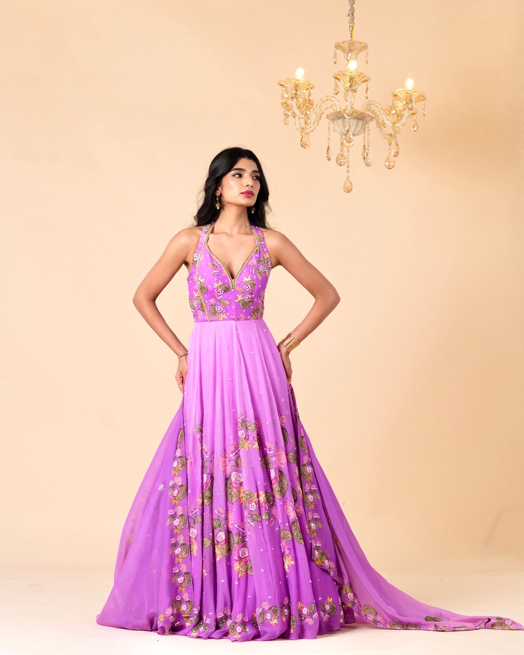 Woman wearing a purple gown with floral embroidery against a beige background