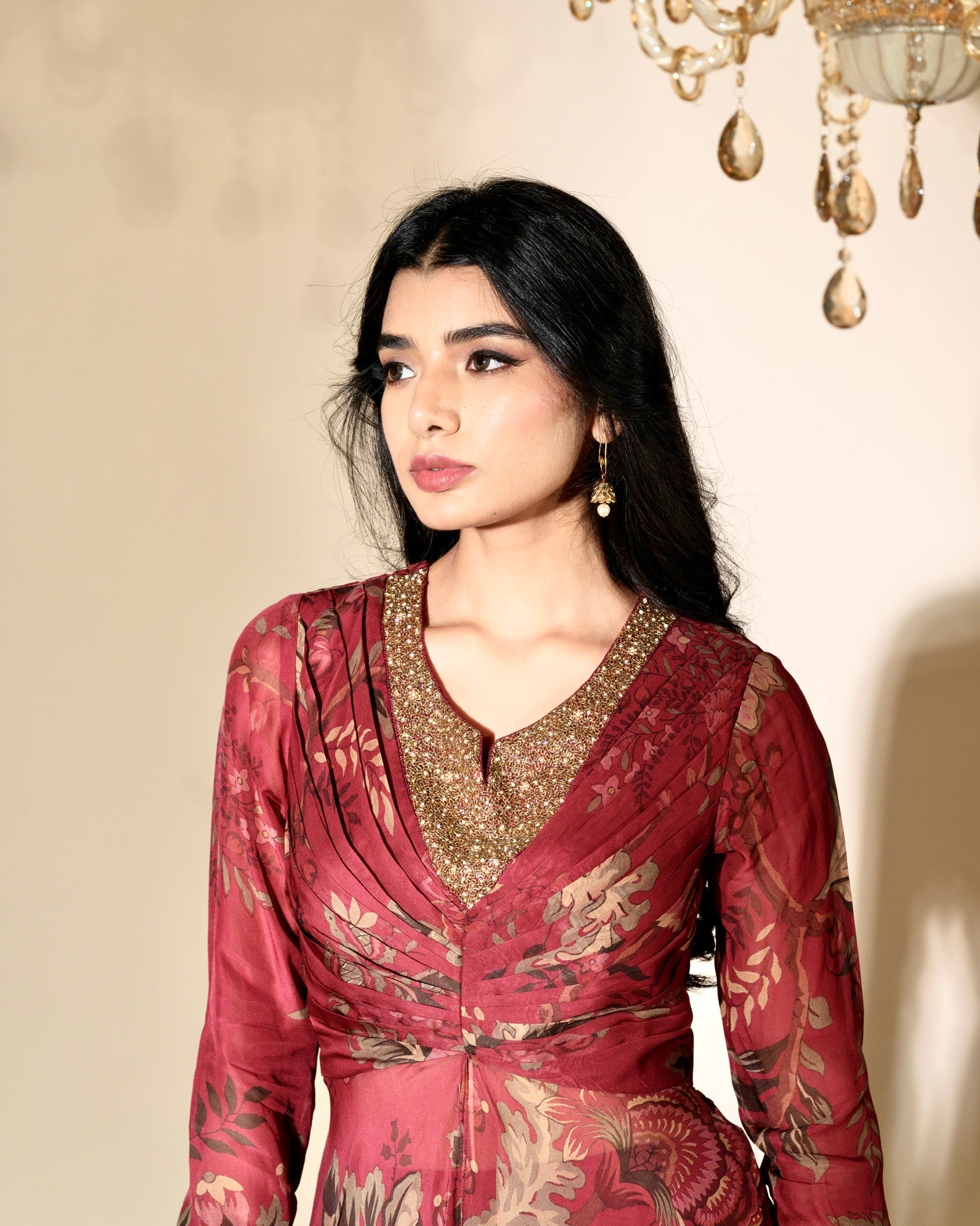 Woman wearing a red and gold traditional outfit with a beige background
