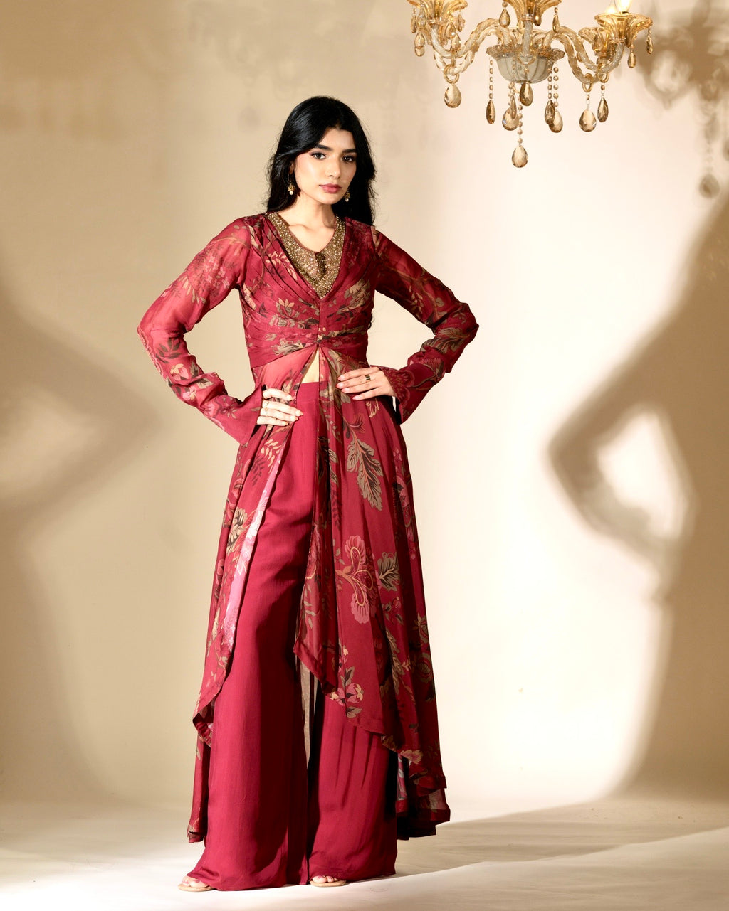 Woman wearing a red embroidered outfit with a chandelier in the background