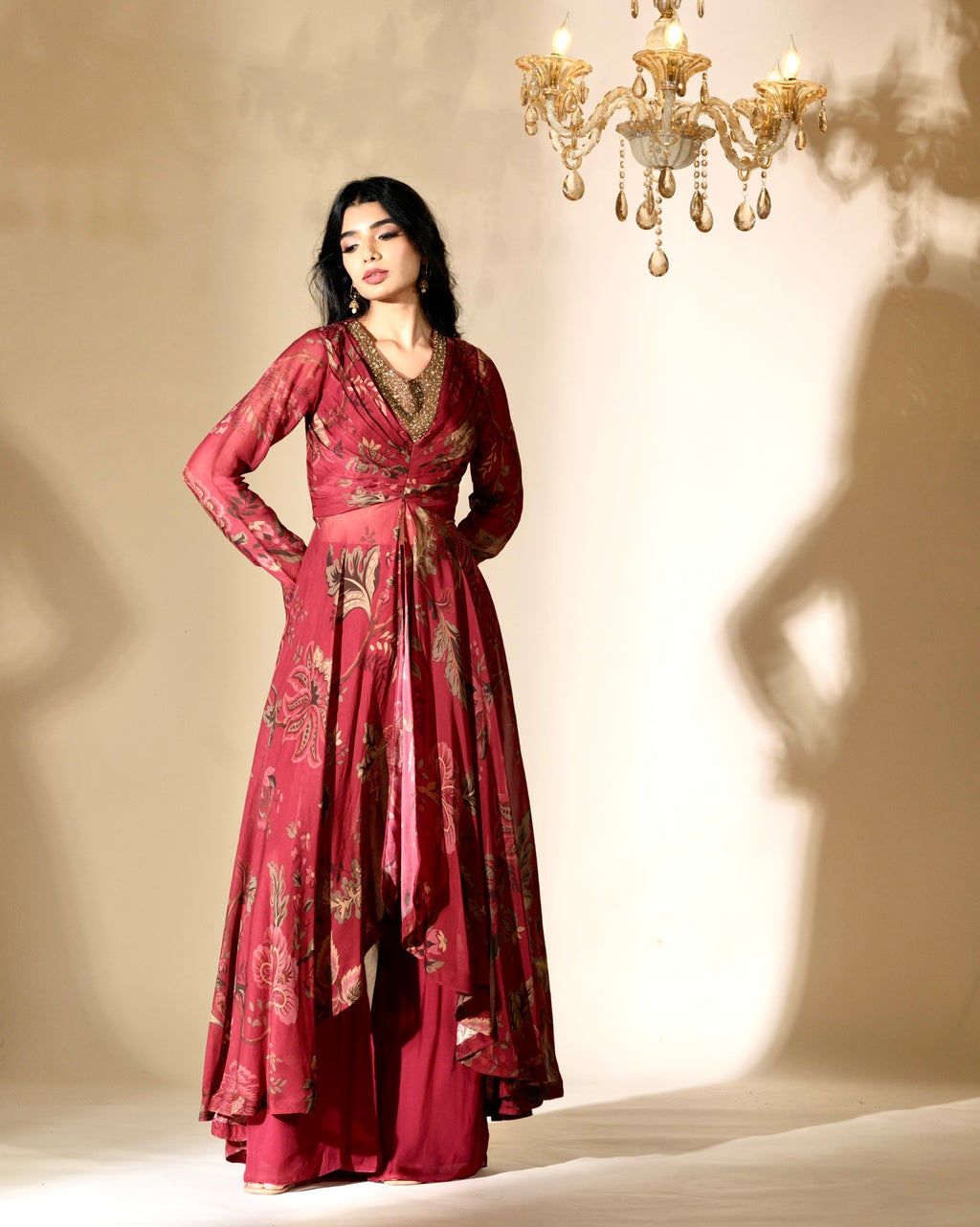 Woman in a red patterned dress standing in front of a chandelier