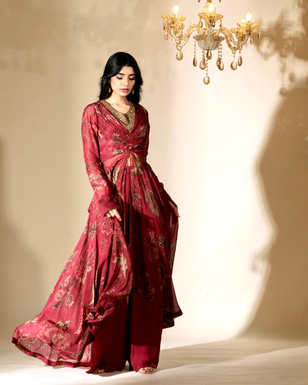 Woman in a red traditional outfit standing under a chandelier