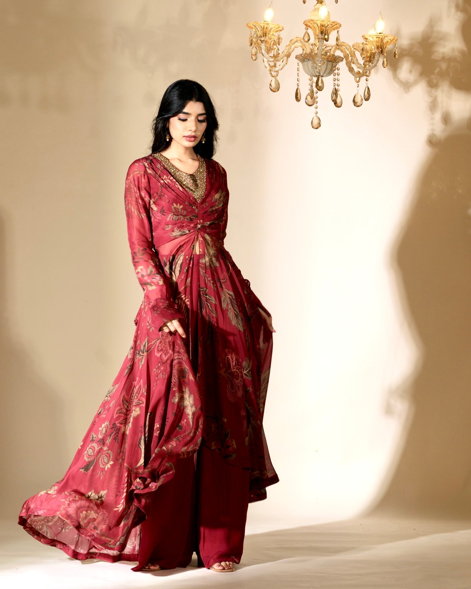 Woman in a red traditional outfit standing under a chandelier