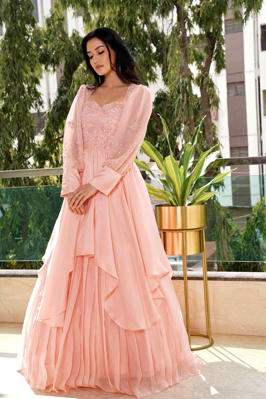 Woman in a pink dress standing outdoors with greenery in the background