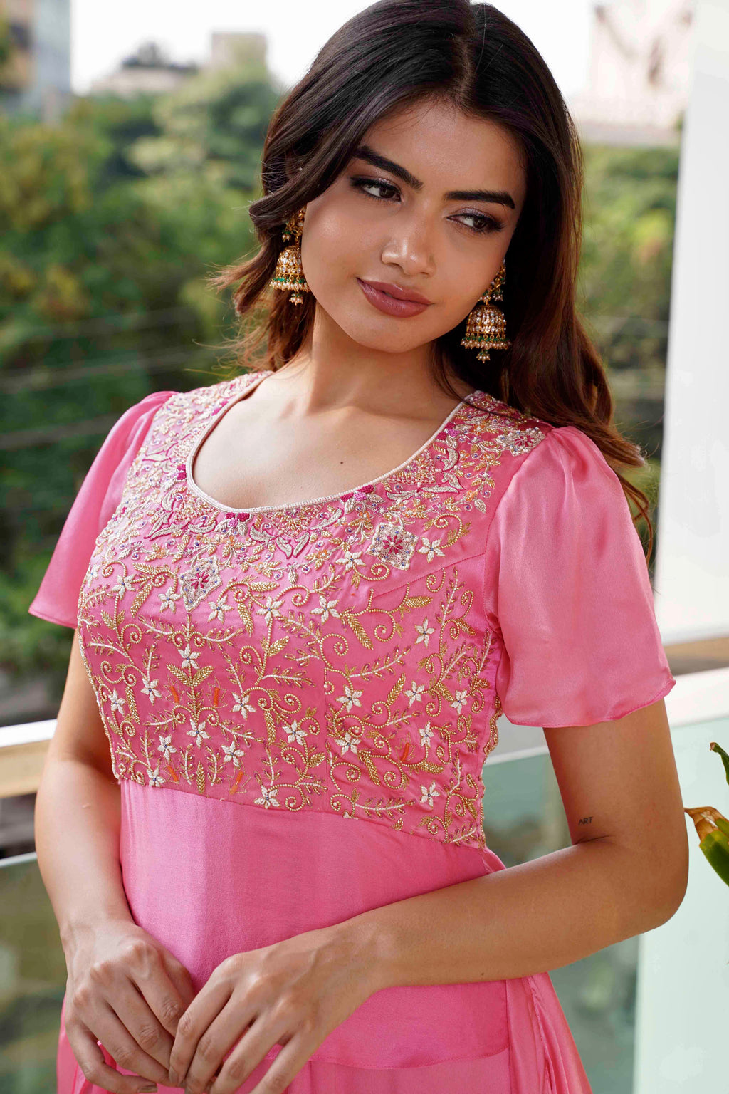 Woman wearing a pink embroidered top and skirt outdoors