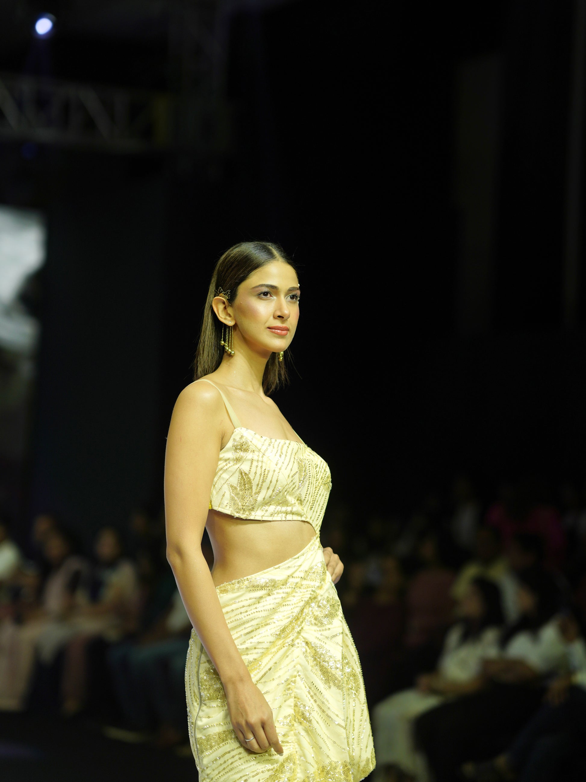 Model wearing a gold outfit on a fashion show runway.