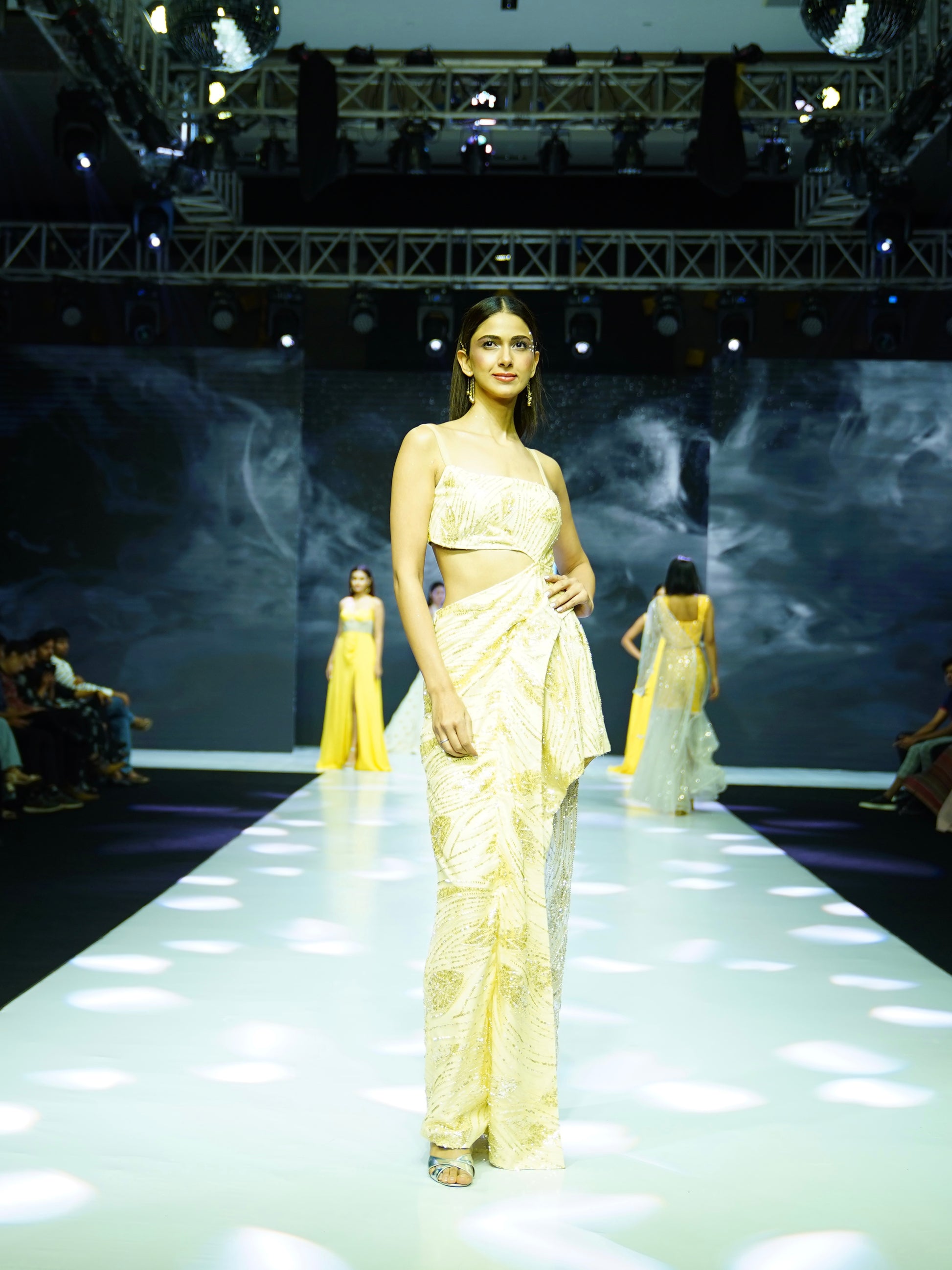 Model in a yellow outfit walking on a fashion show runway.