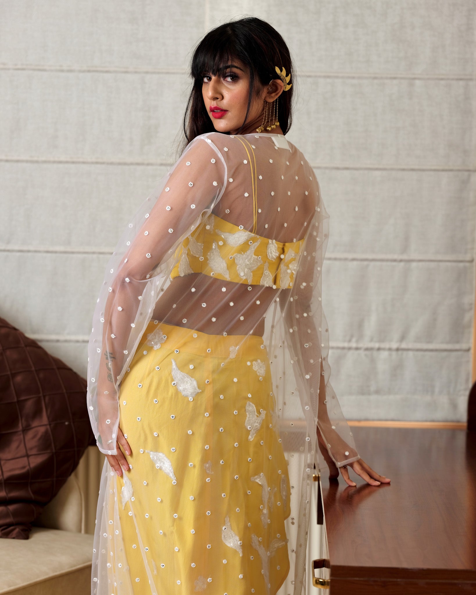 Woman wearing a yellow dress with a sheer overlay against a neutral background