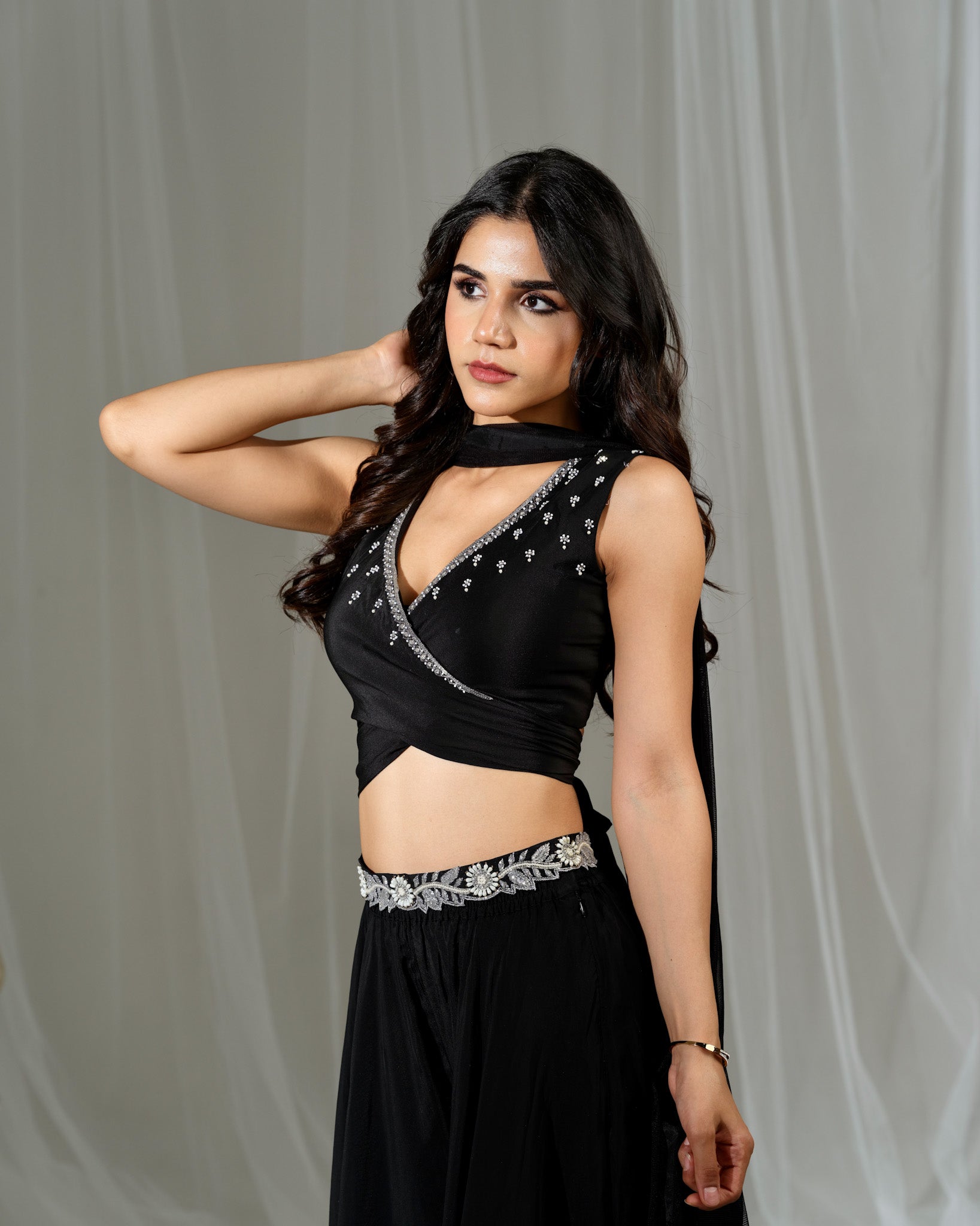 Woman wearing a black saree with silver details against a gray background
