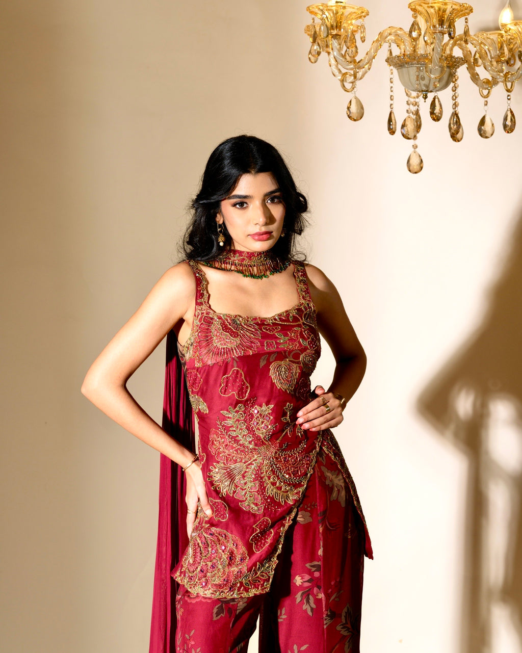 Woman wearing a red and gold traditional outfit with a chandelier in the background
