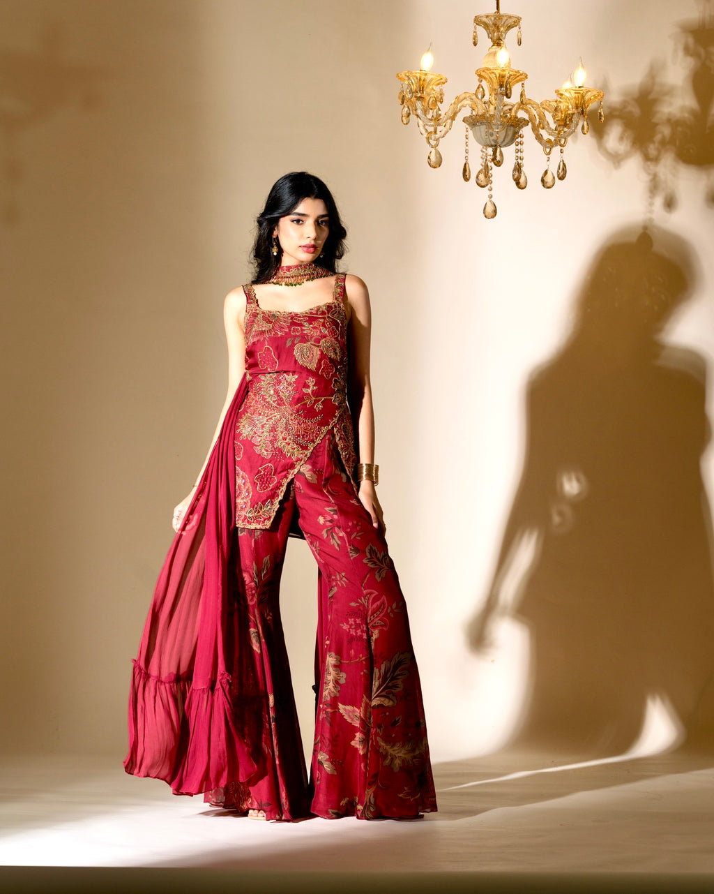 Woman wearing a red patterned outfit with a chandelier in the background