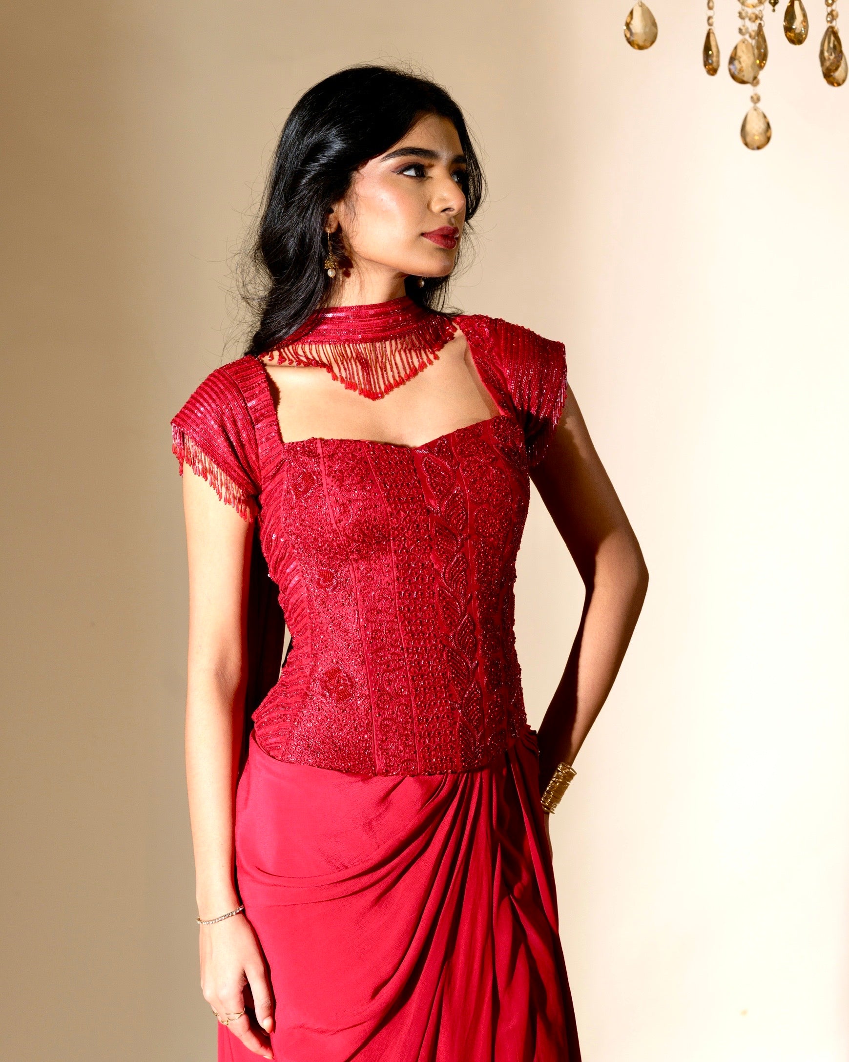 Woman wearing a red saree with a matching blouse against a beige background