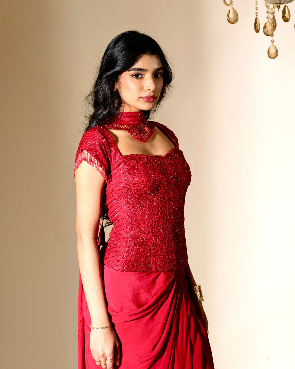 Woman wearing a red saree with a matching blouse against a beige background