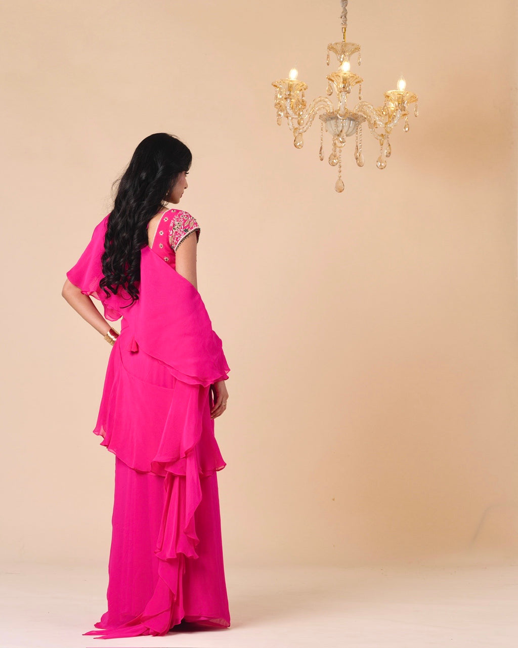 Woman wearing a bright pink saree with a beige background