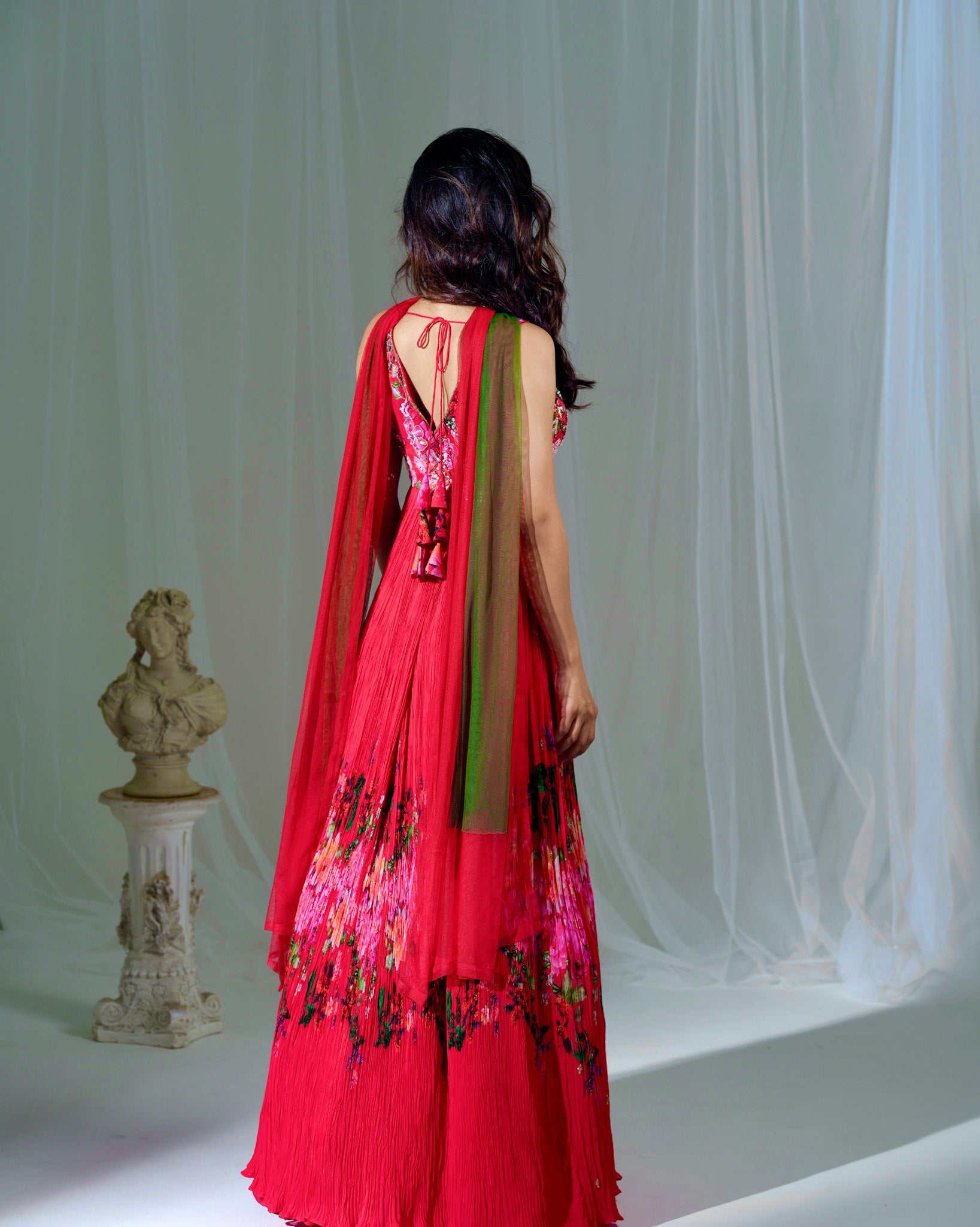 Woman wearing a red floral dress with a white curtain background