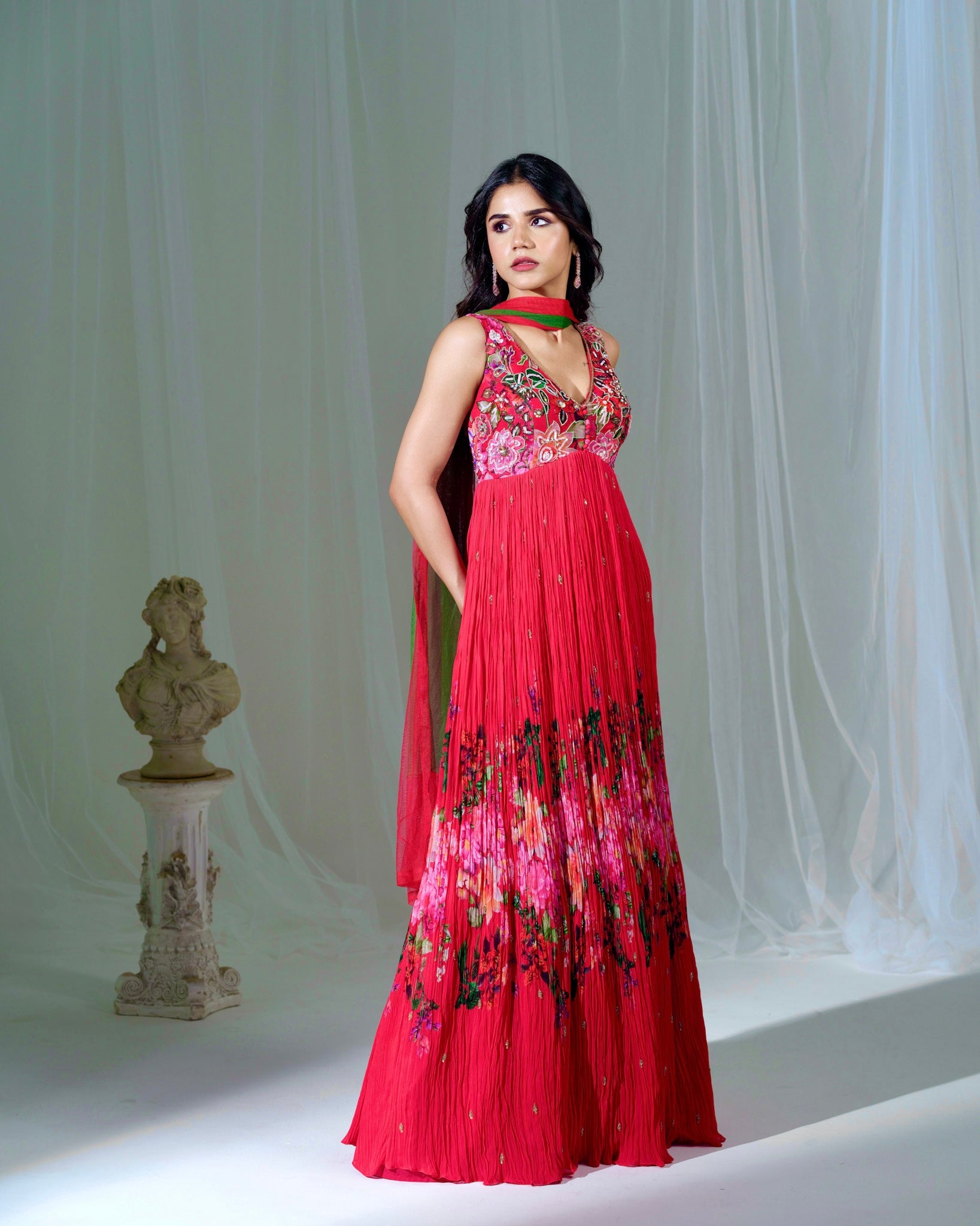 Woman wearing a red floral dress against a white curtain background