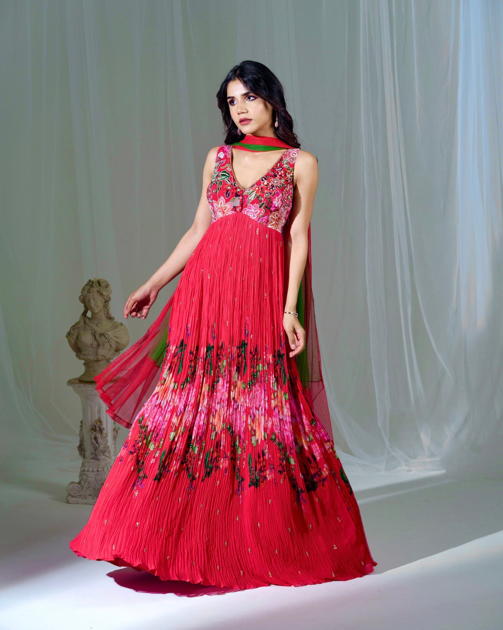 Woman wearing a red floral dress with a white curtain background