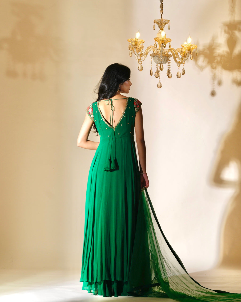 Woman in a green evening gown standing in front of a chandelier