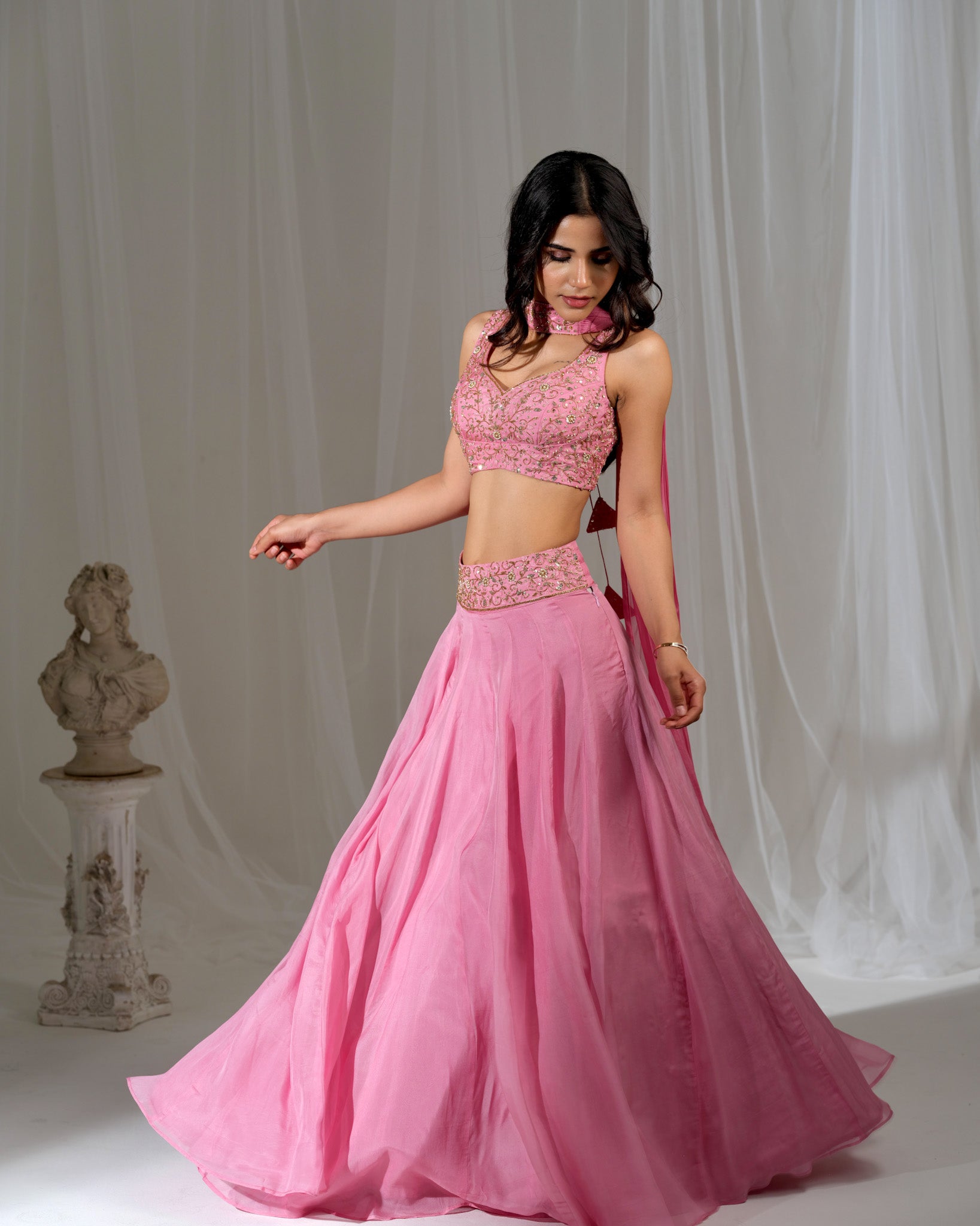 Woman wearing a pink traditional outfit with a white curtain background