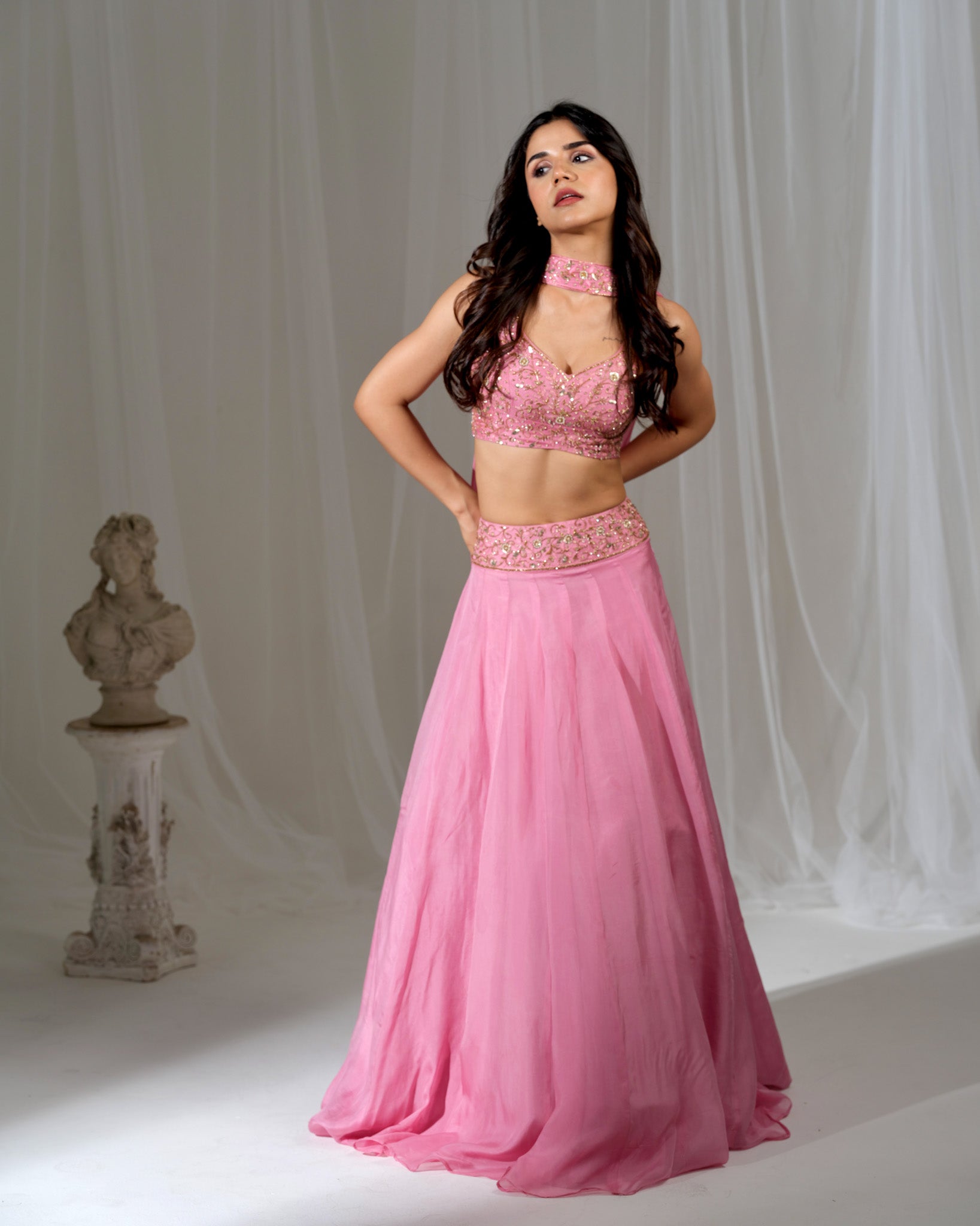 Woman wearing a pink traditional outfit with a white curtain background
