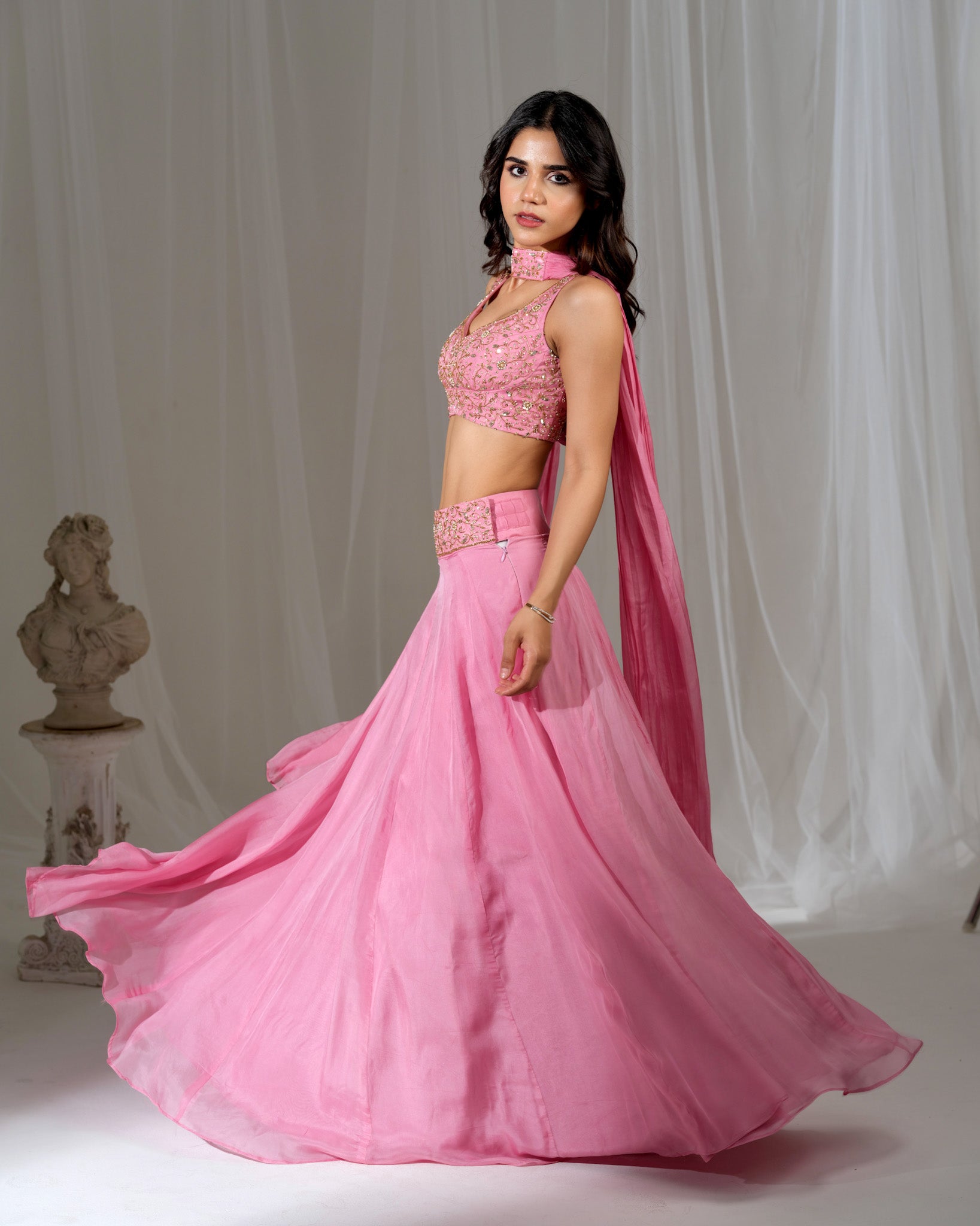 Woman wearing a pink traditional outfit with a flowing skirt against a white background