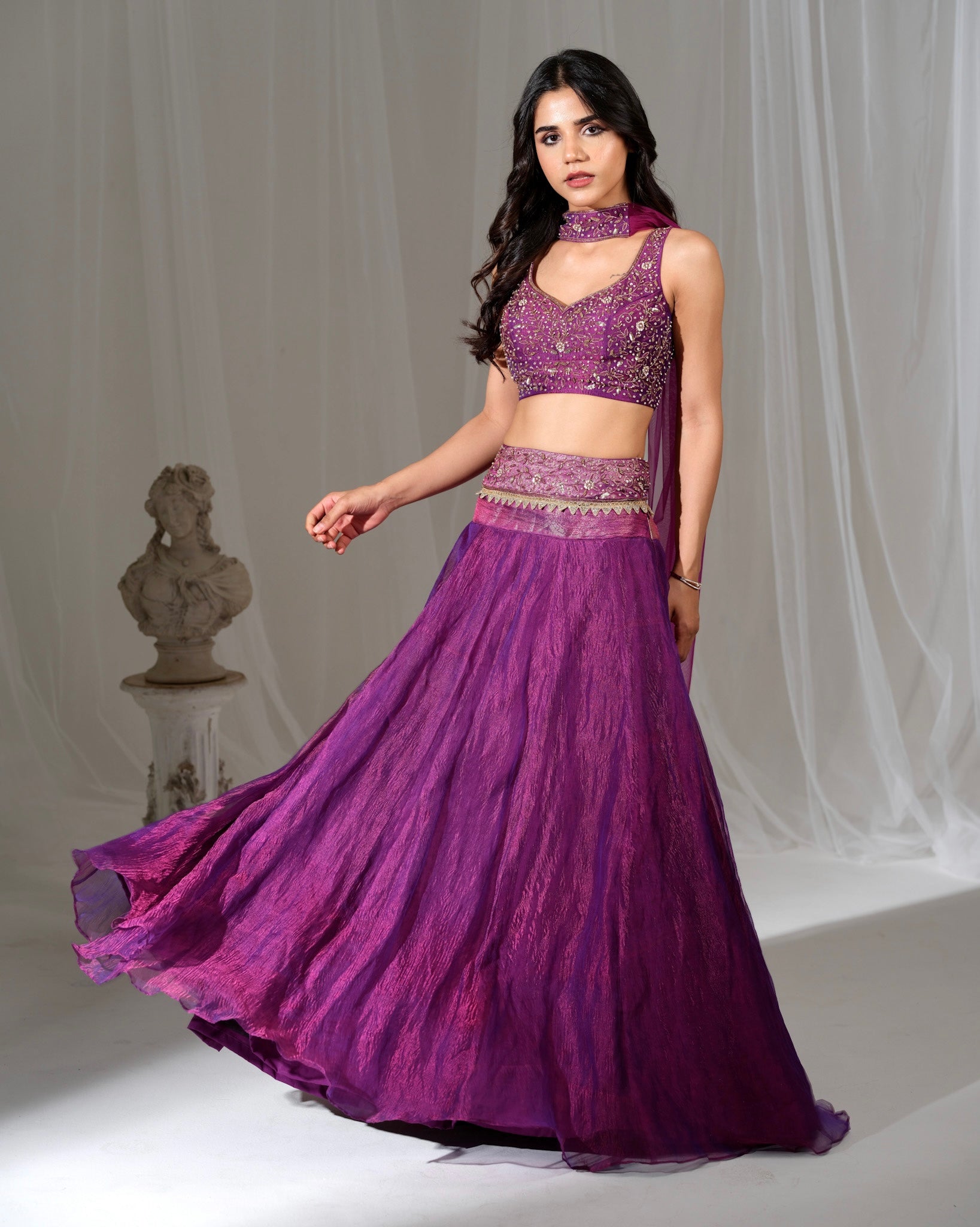 Woman wearing a purple traditional outfit with a flowing skirt on a white background