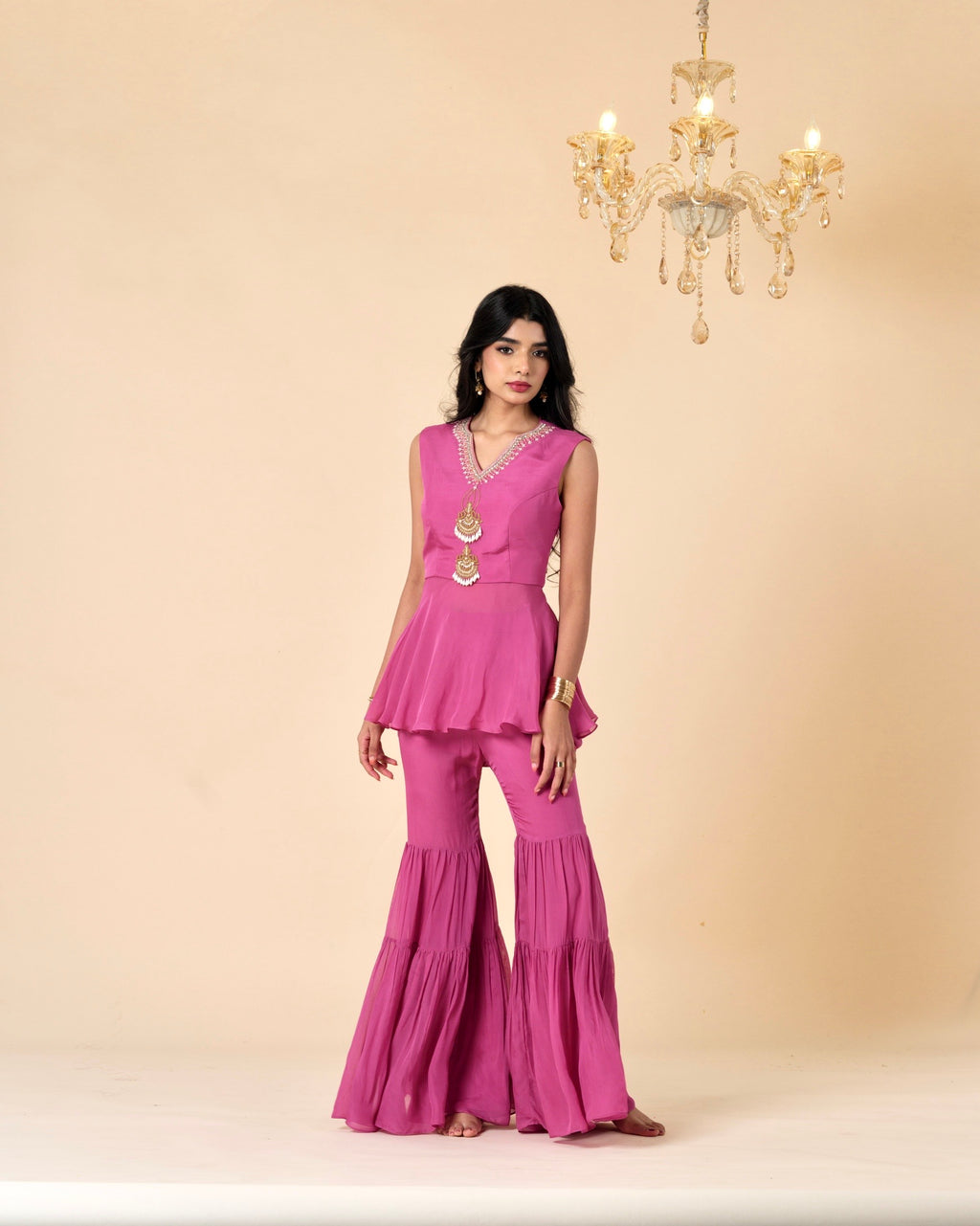 Woman wearing a pink outfit with a chandelier in the background