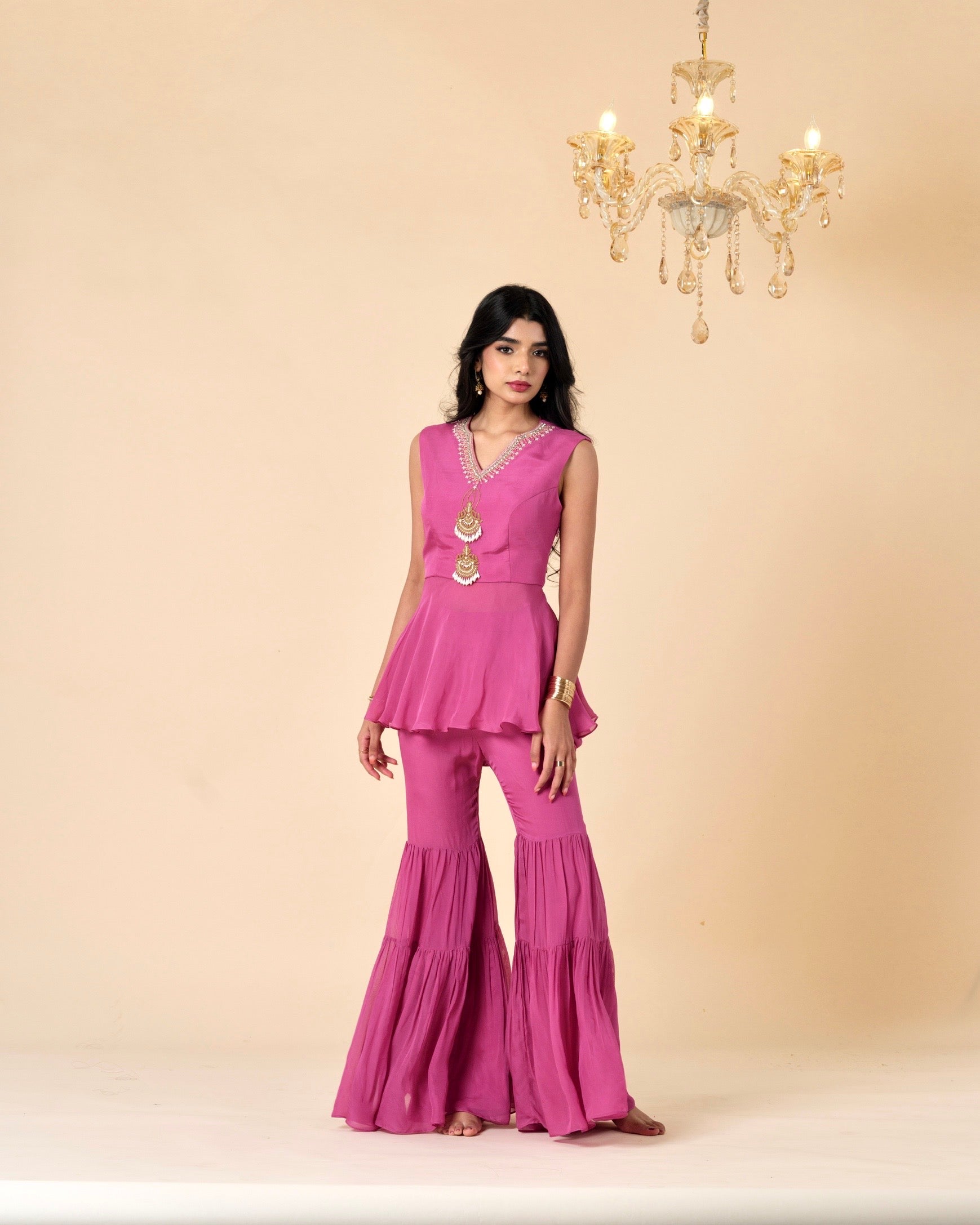 Woman wearing a pink outfit with a chandelier in the background