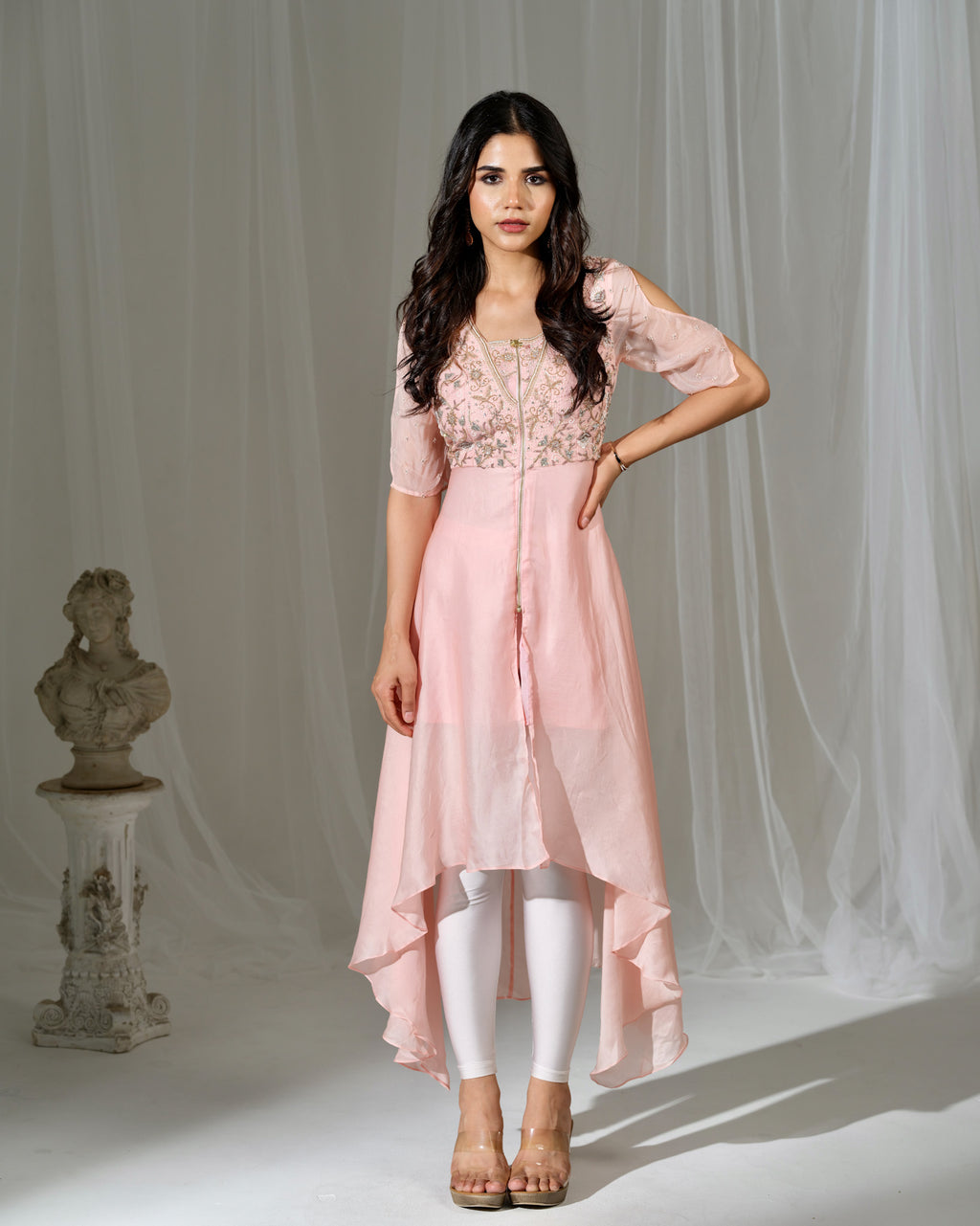 Woman wearing a pink outfit with white leggings against a neutral background