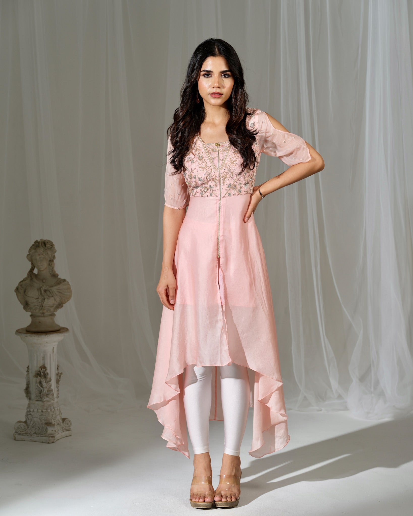 Woman wearing a pink outfit with white leggings against a neutral background