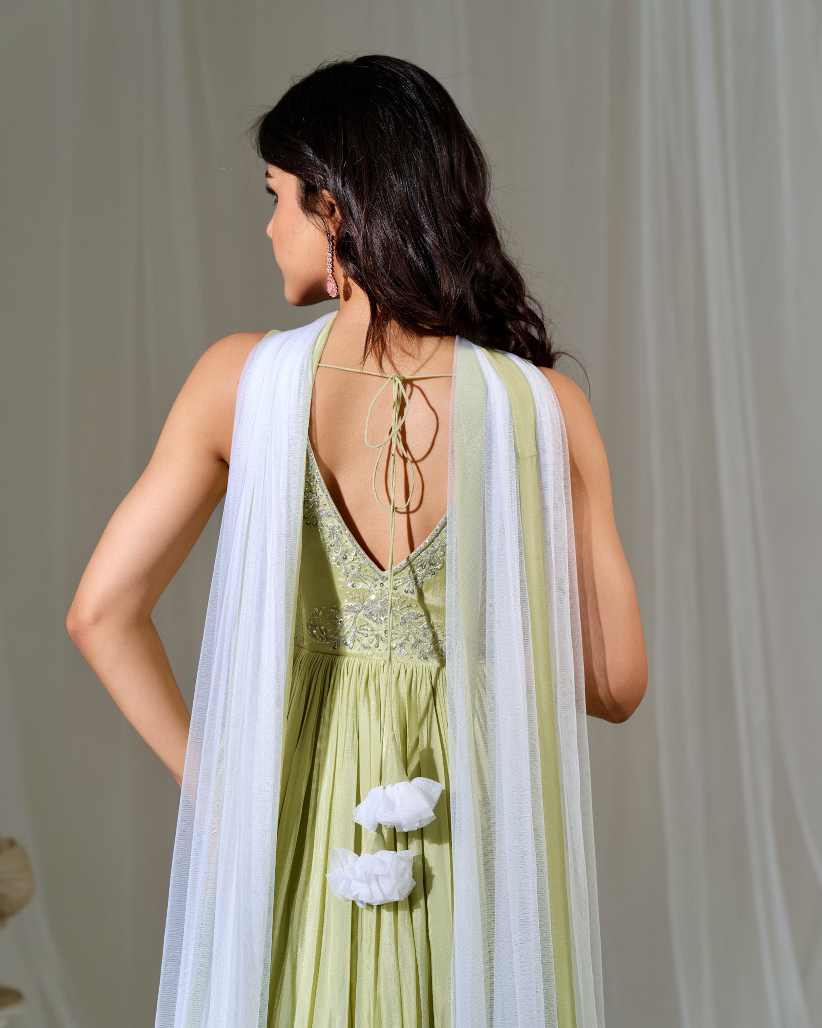 Woman wearing a green dress with a white dupatta against a neutral background