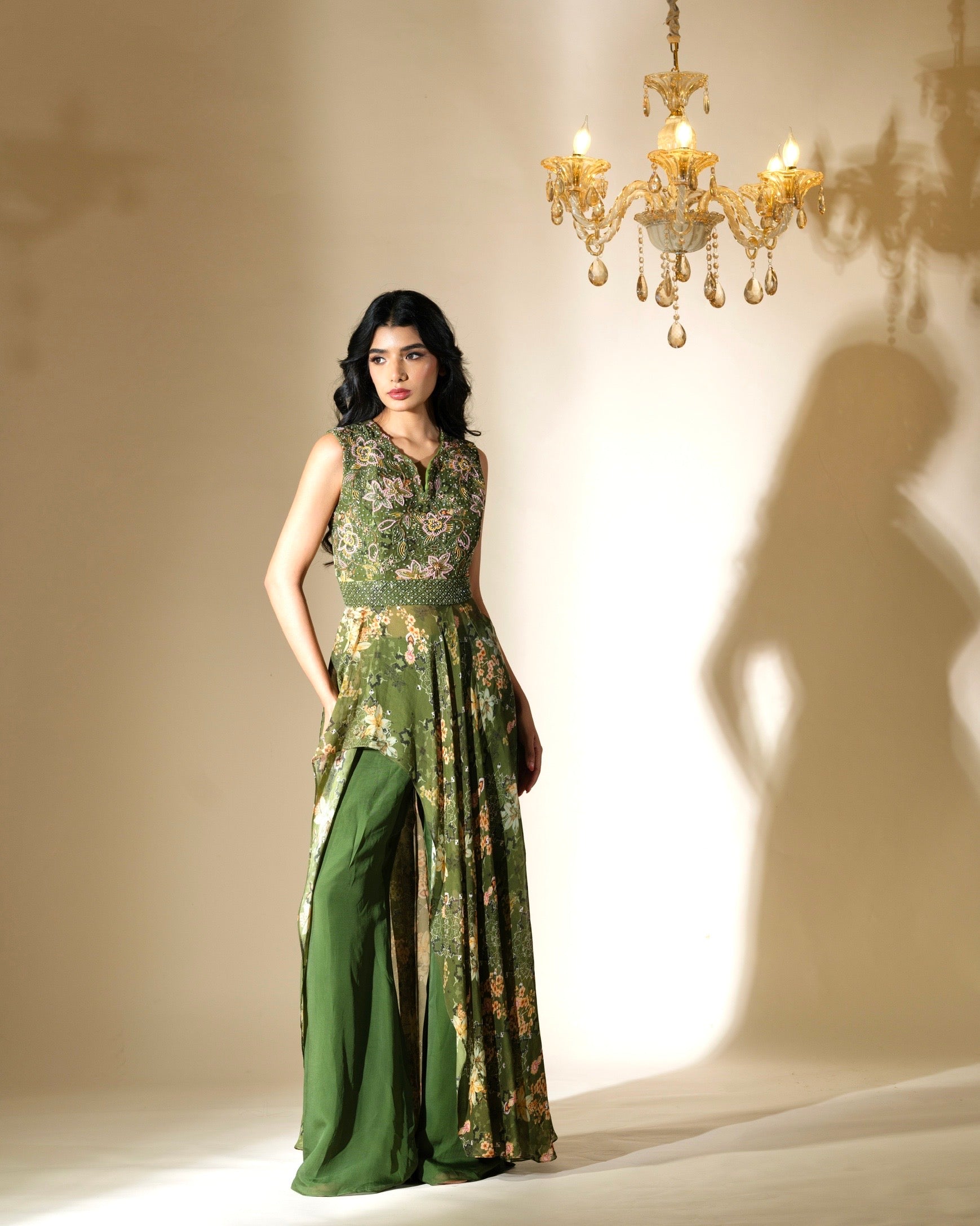 Woman wearing a green floral dress standing in front of a chandelier.