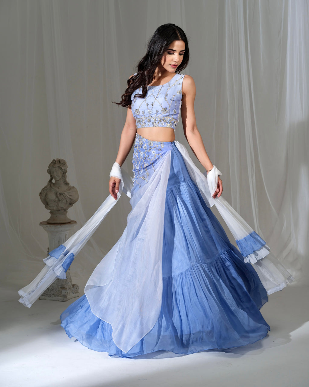 Woman in a blue and white traditional outfit with a white background