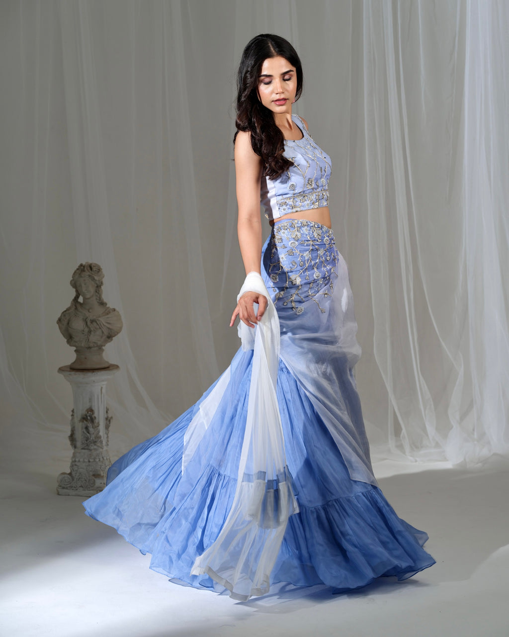 Woman in a blue and white traditional outfit with a white background