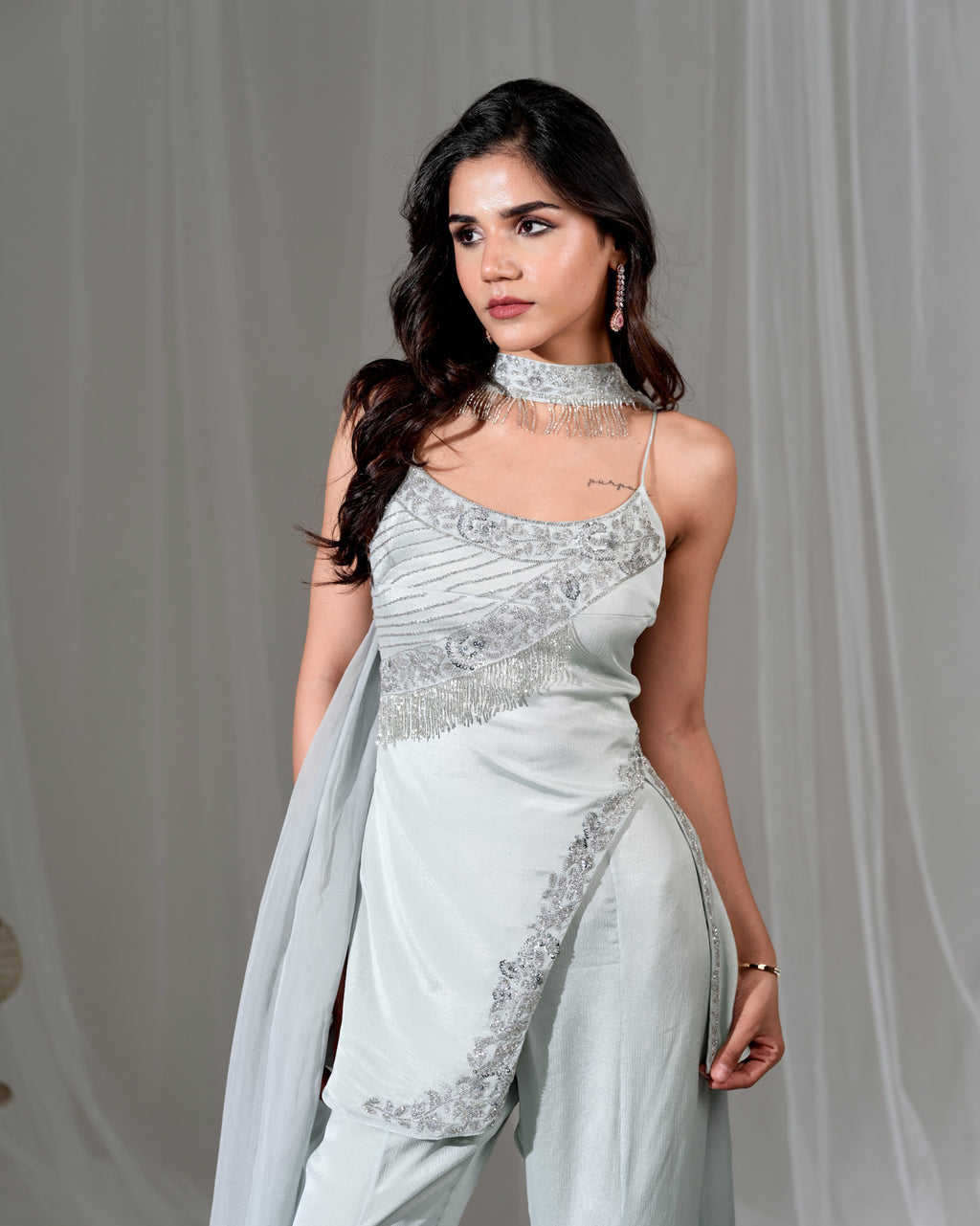 Woman wearing a light blue saree with silver embroidery against a plain background