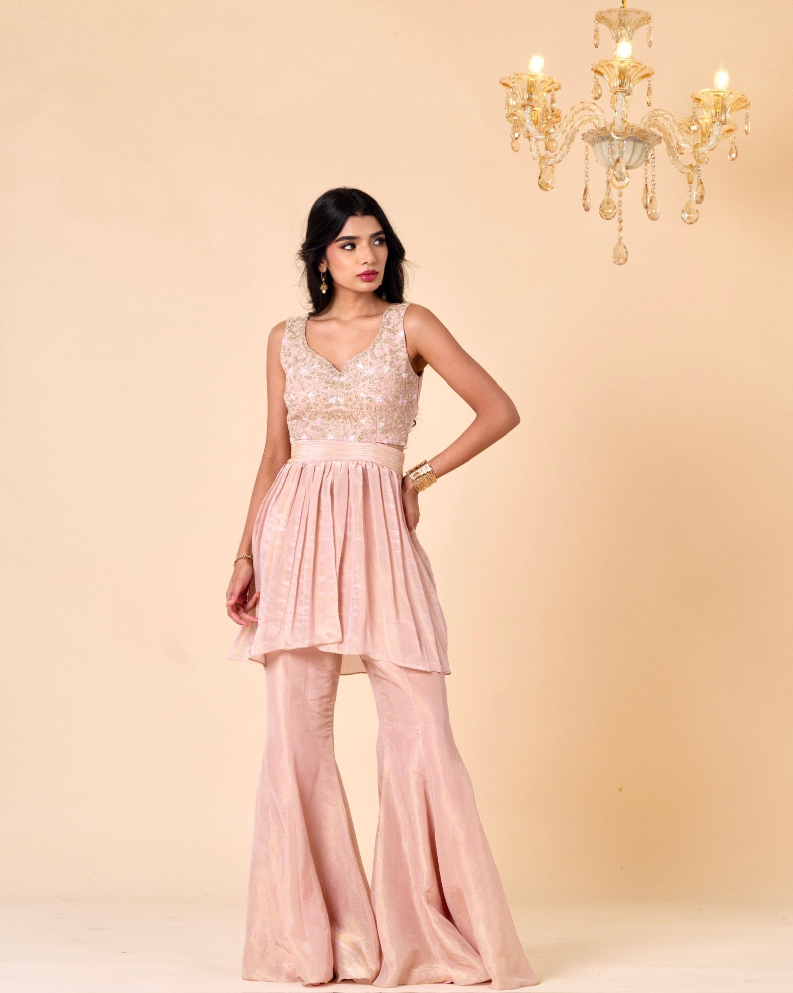 Woman wearing a pink dress with a chandelier in the background