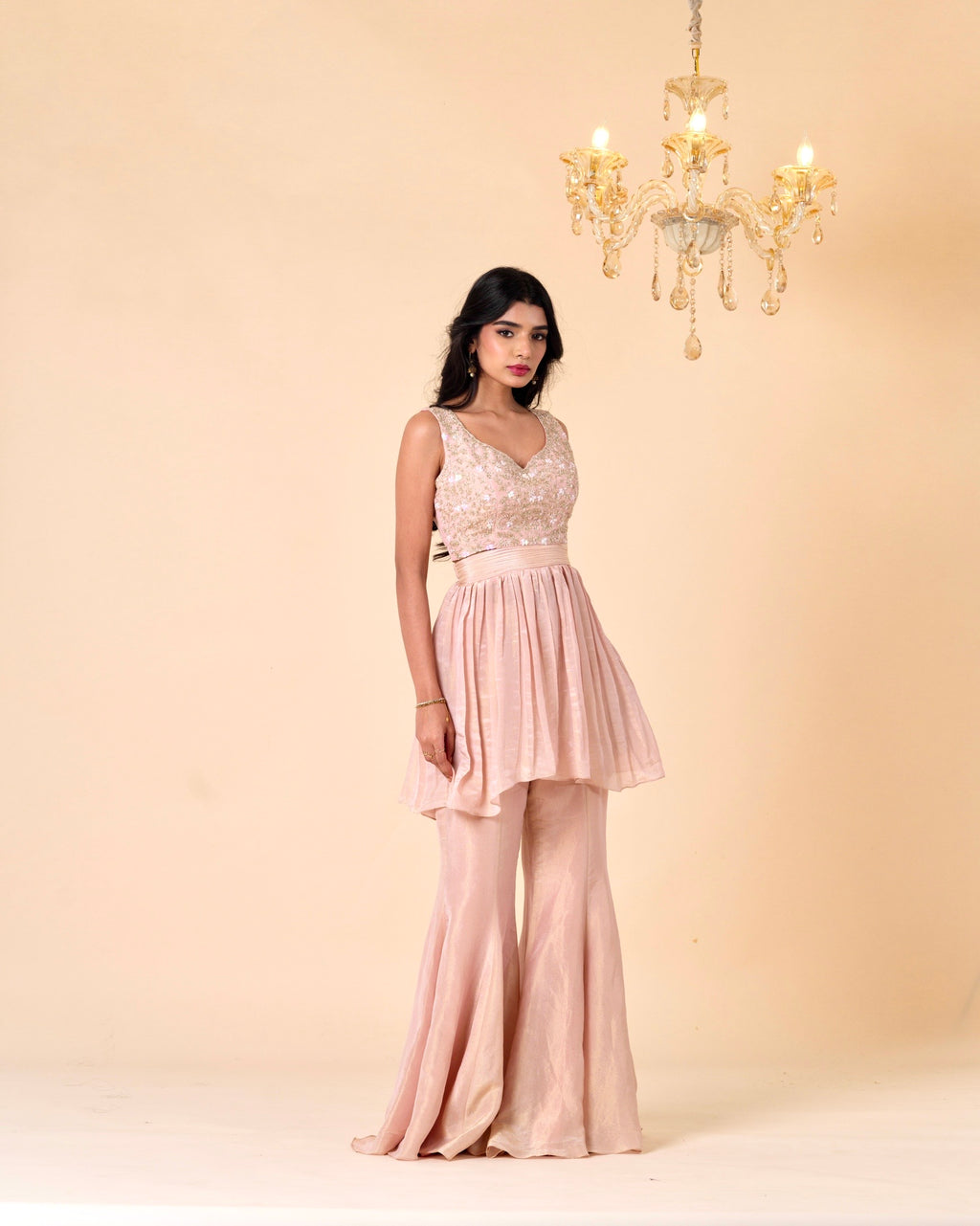 Woman wearing a pink dress with a chandelier in the background