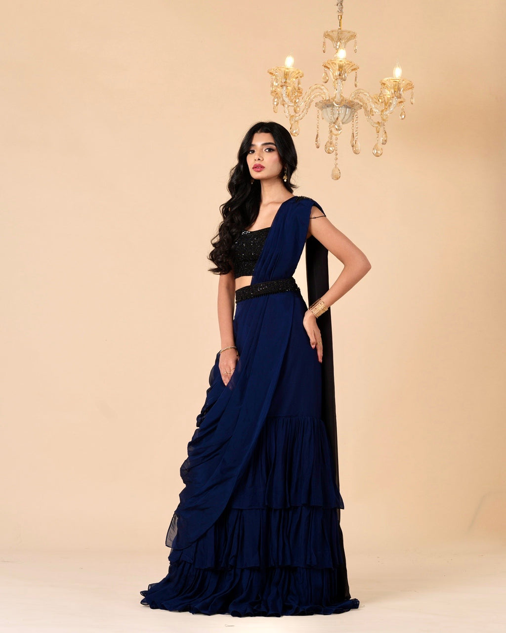 Woman wearing a navy blue saree with a black blouse against a beige background