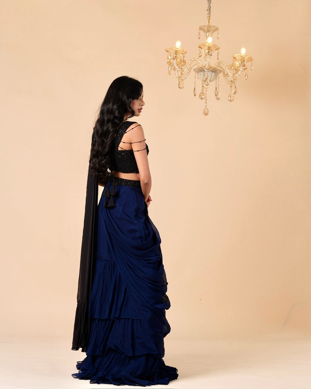 Woman in a black and blue traditional outfit with a chandelier in the background