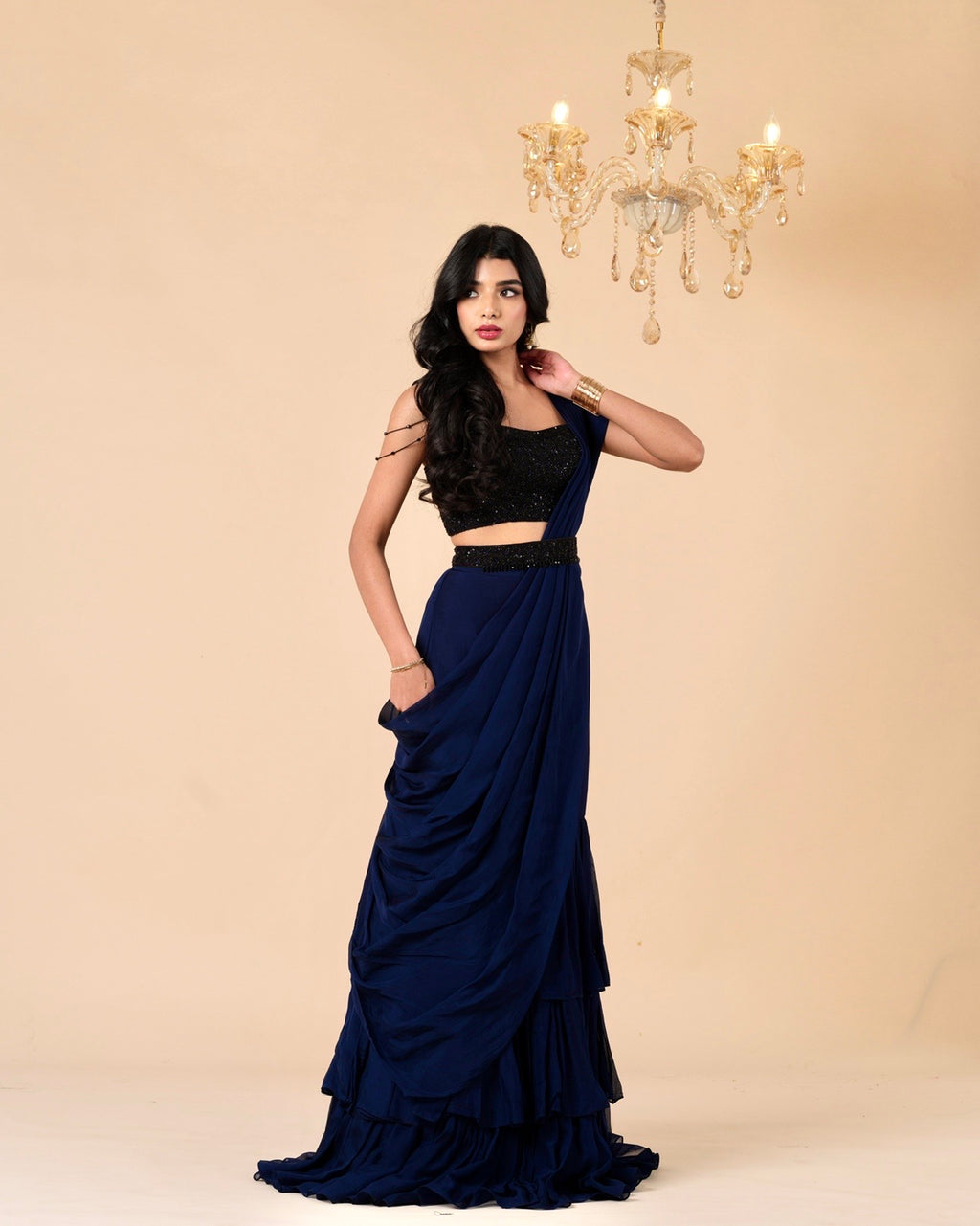 Woman wearing a black top and navy blue skirt with a beige background