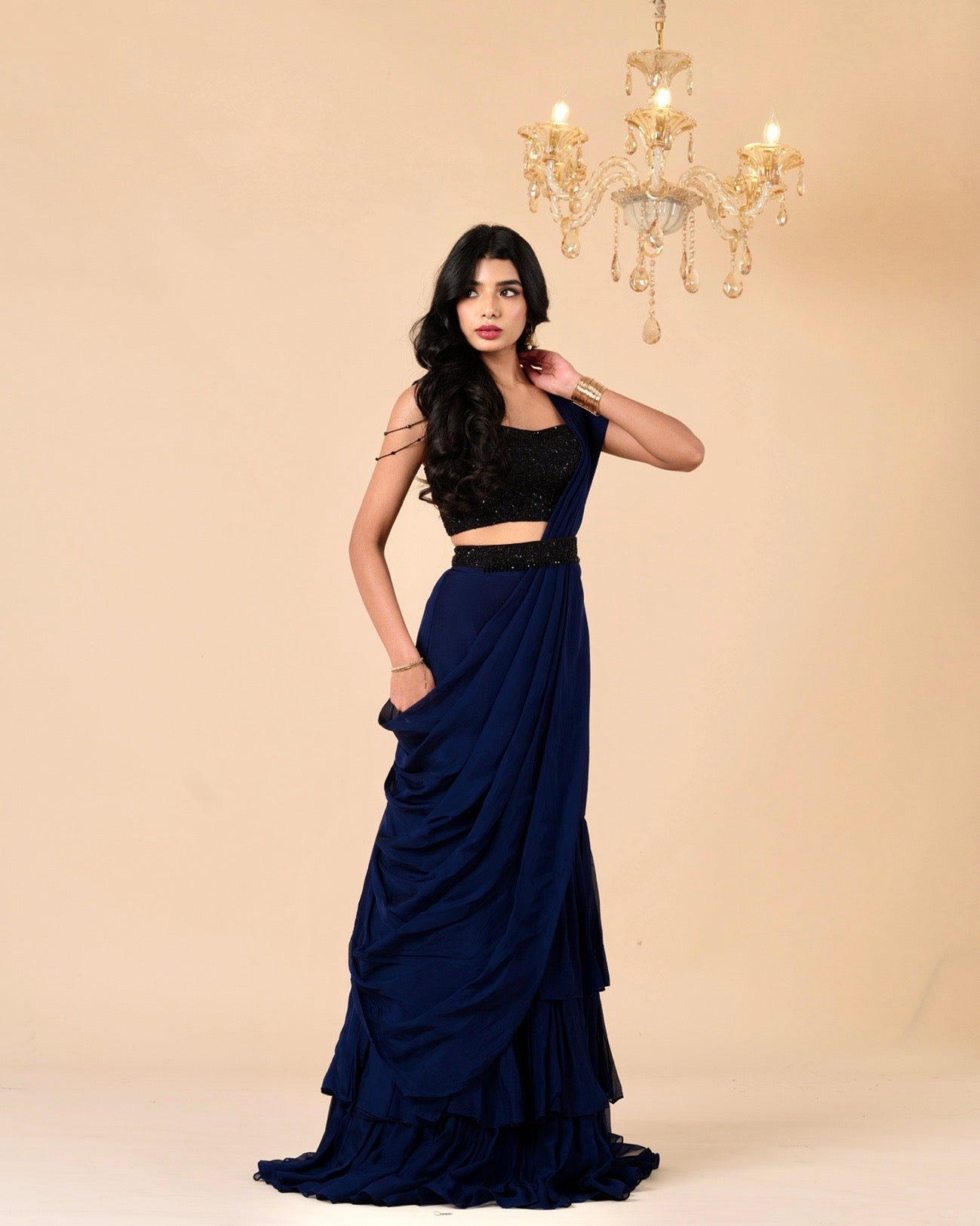 Woman wearing a black top and navy blue skirt with a beige background