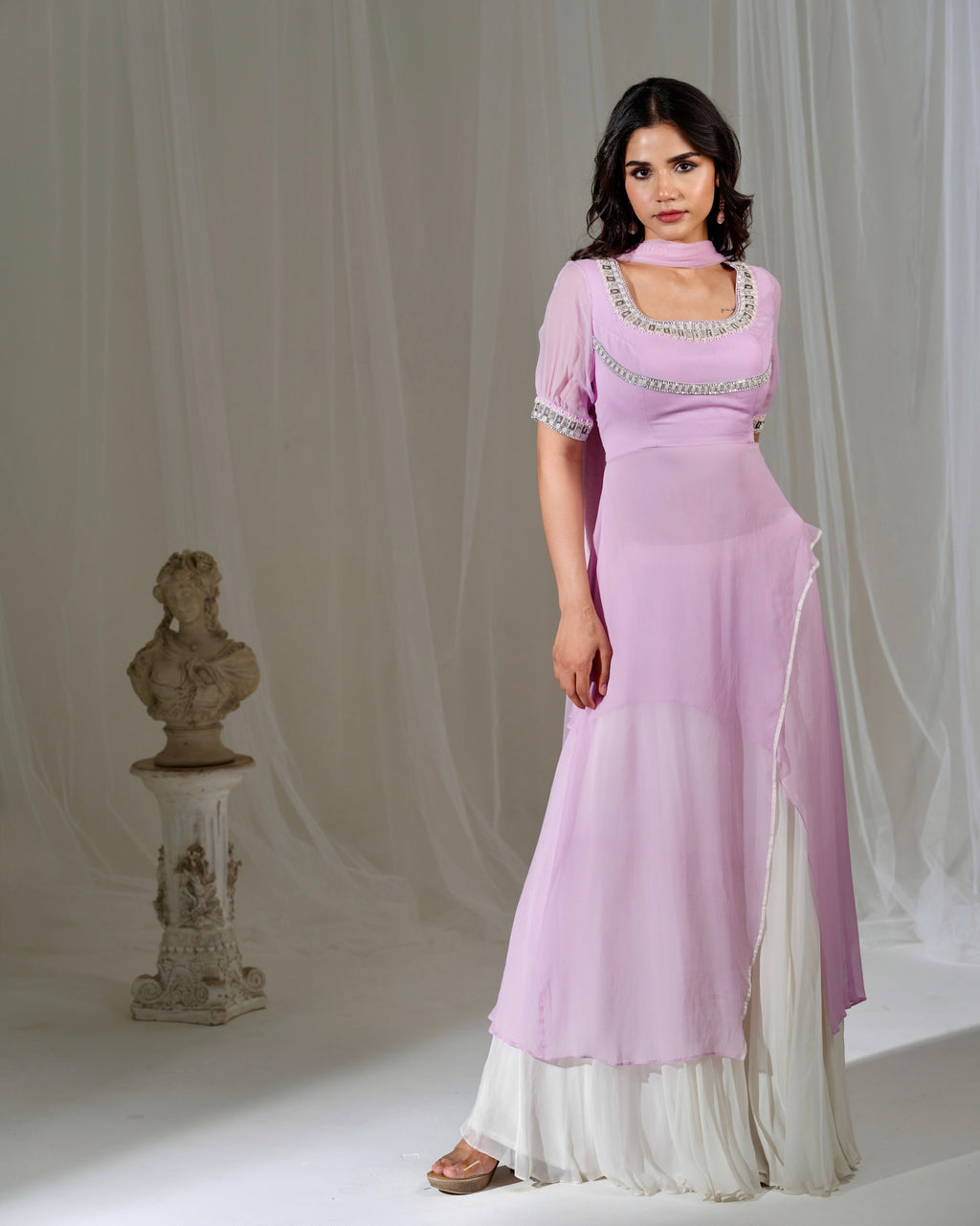 Woman wearing a light purple dress with white trim against a neutral background