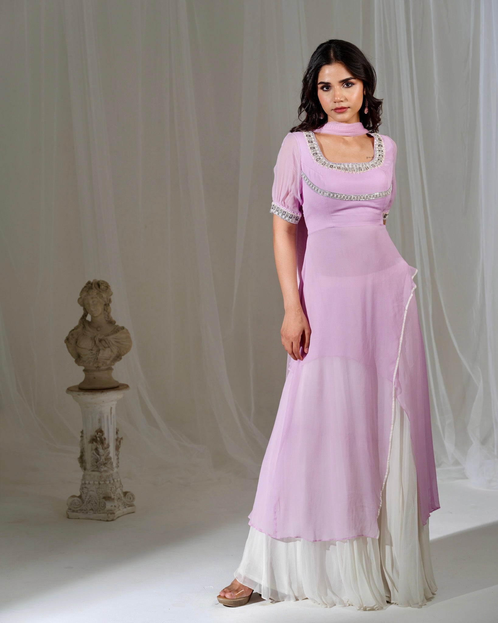 Woman wearing a light purple dress with white trim against a neutral background