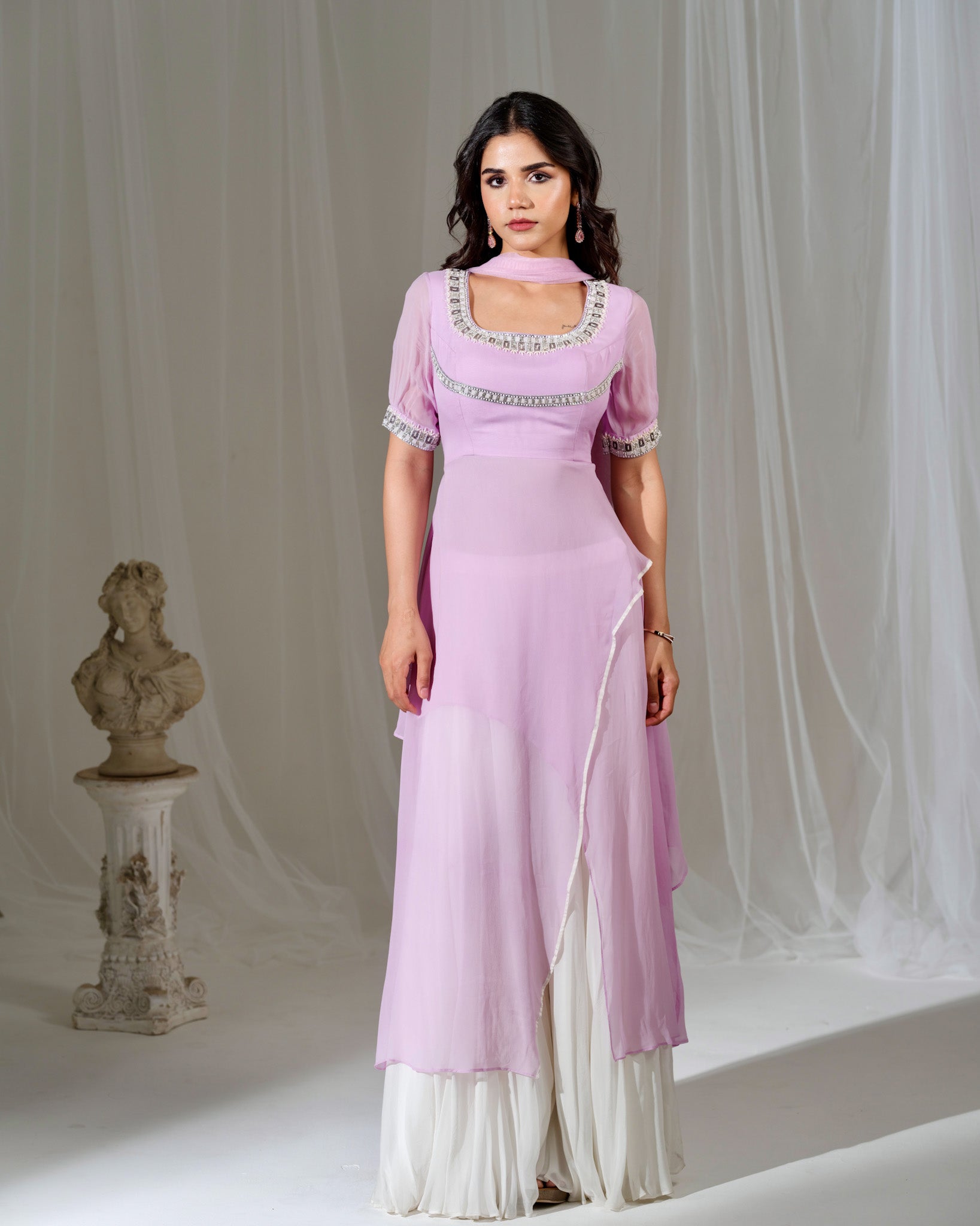 Woman wearing a light purple dress with white accents in a studio setting.