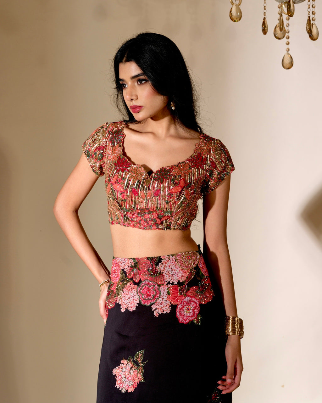 Woman wearing a floral blouse and black skirt against a neutral background