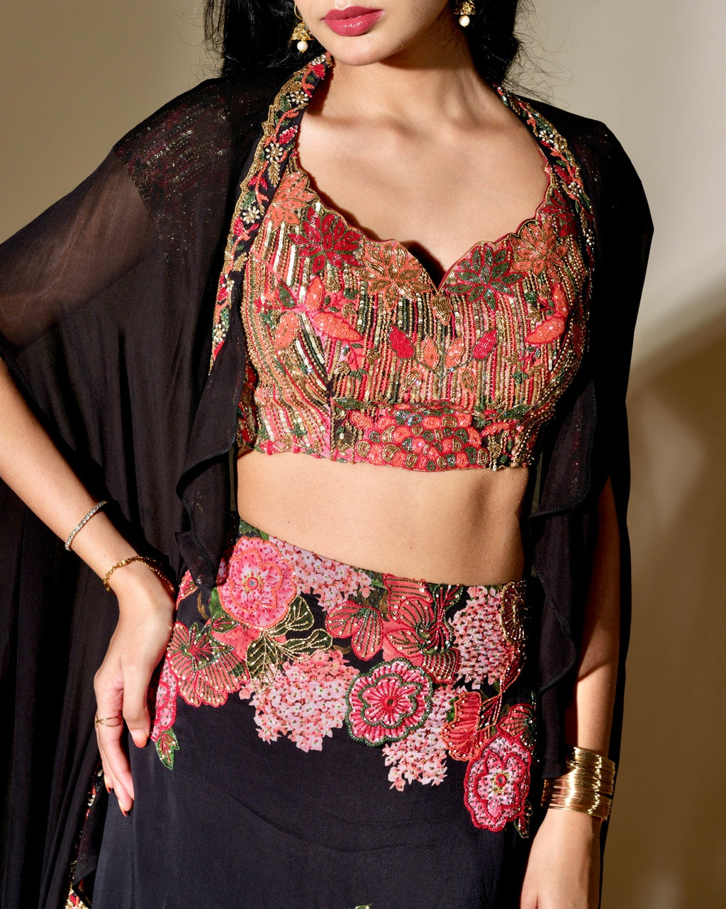 Woman wearing a floral blouse with a black dupatta against a neutral background