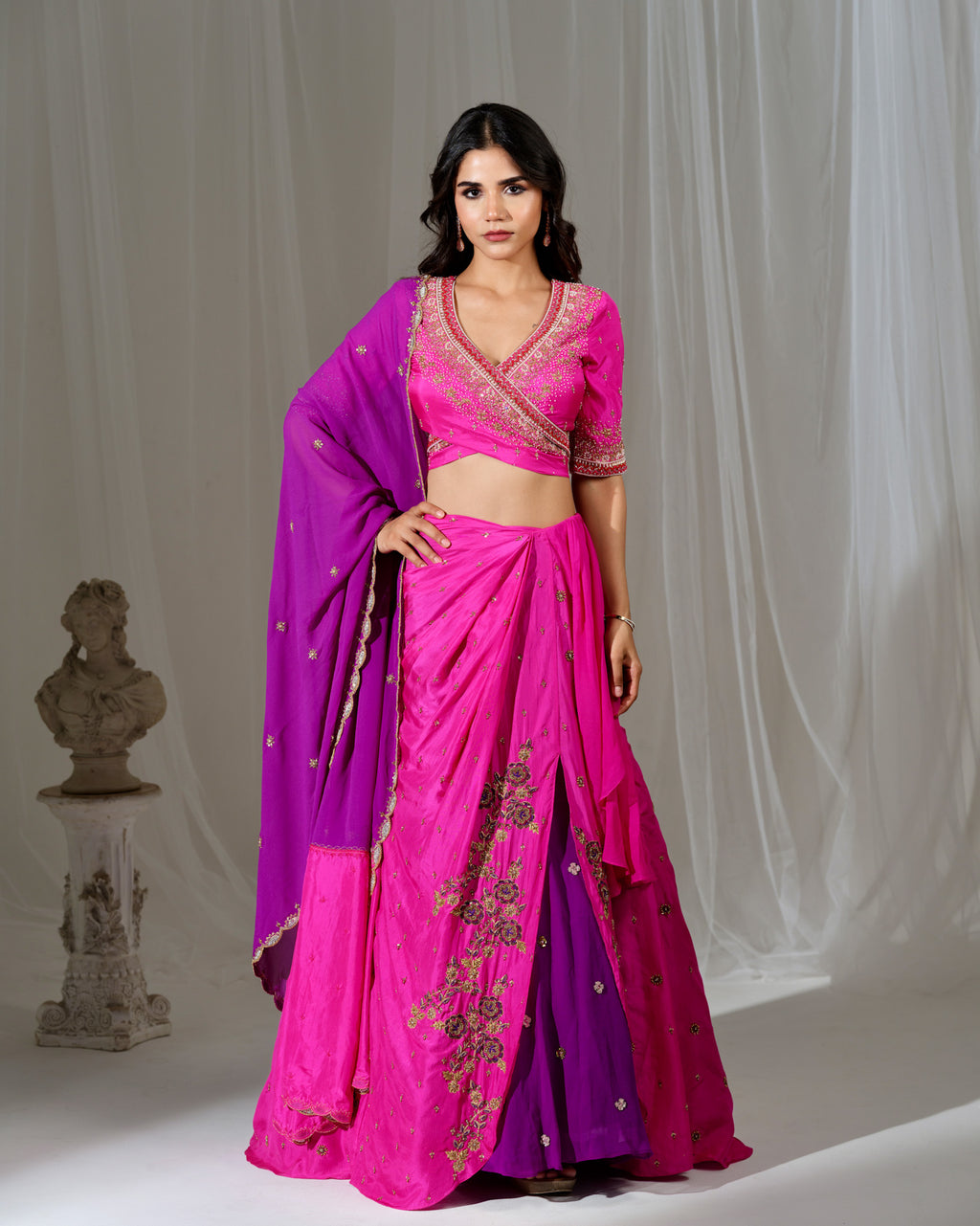 Woman wearing a pink and purple saree with a white background